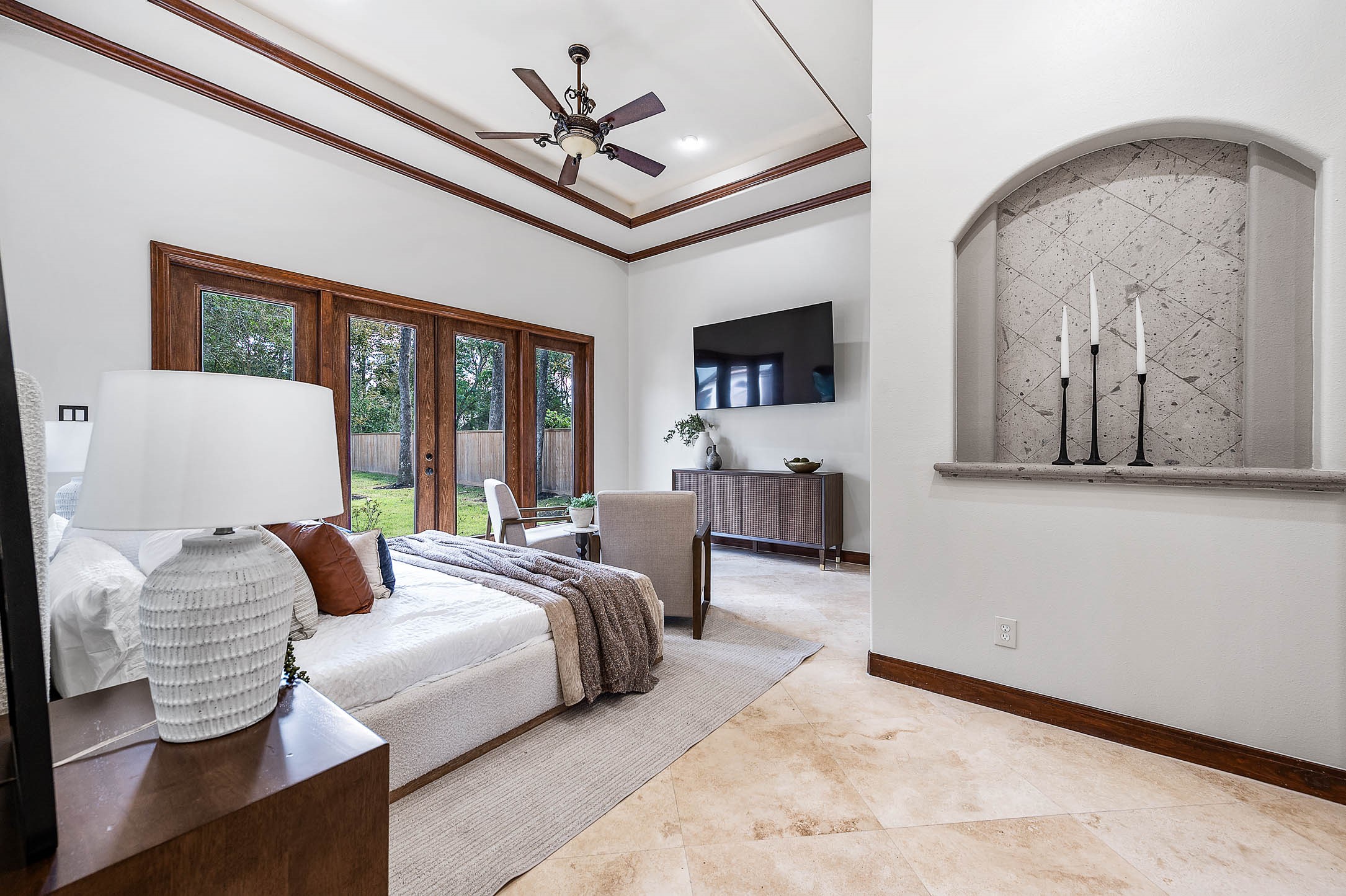 The first-floor primary suite features a tray ceiling with crown molding and a wall of French doors opening to the backyard.