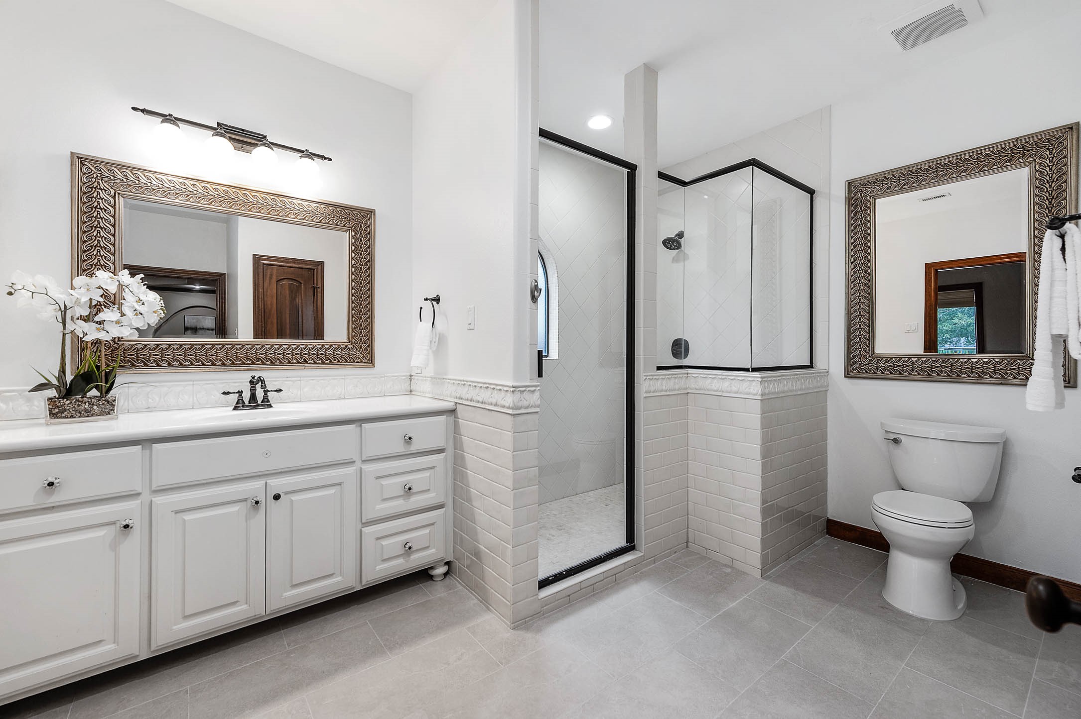 The updated secondary bath features new tile, a walk-in shower, and a single vanity.