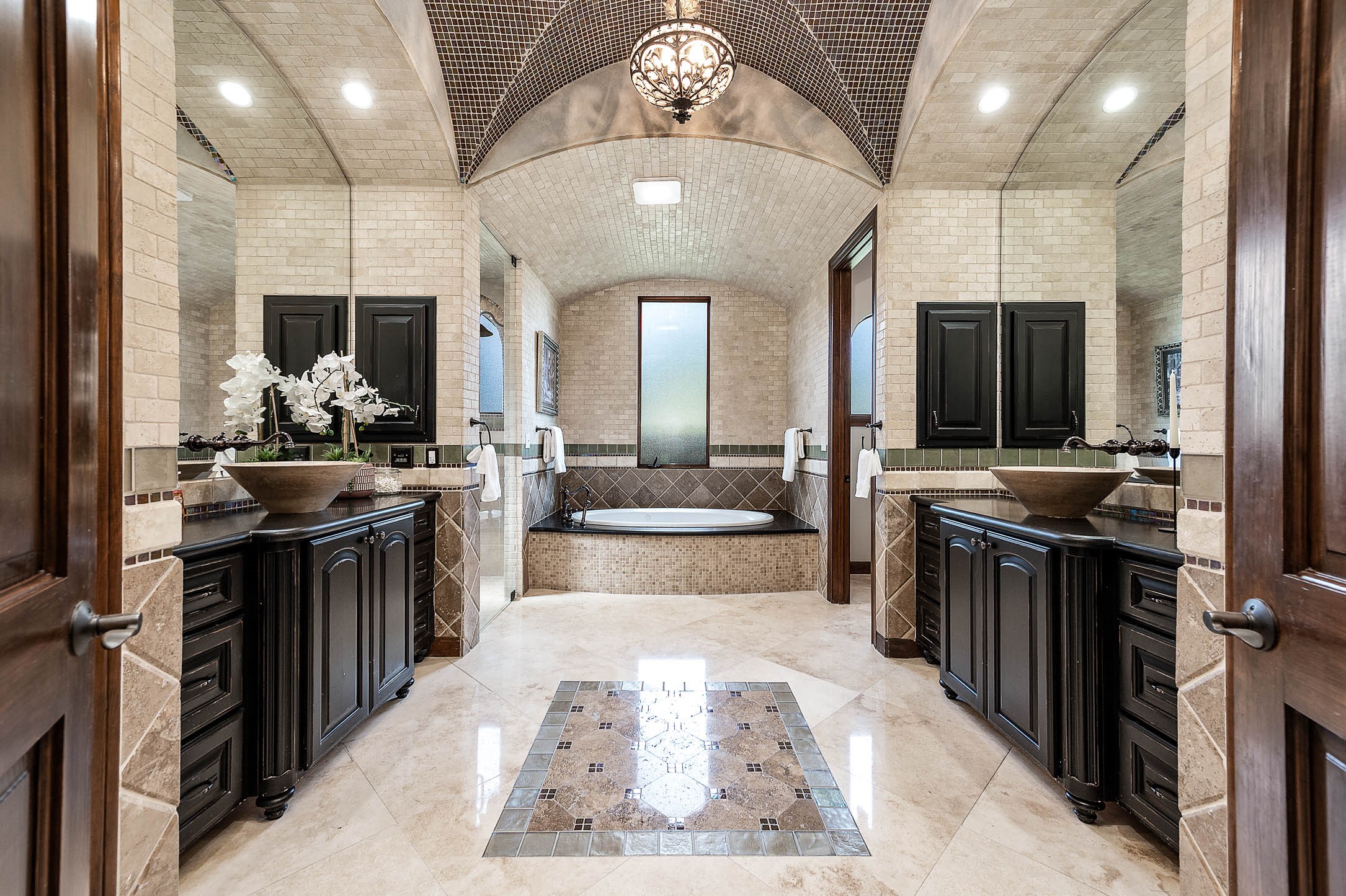 The spa-like primary bath features dual vanities with vessel sinks beneath a barrel-vaulted tile ceiling.