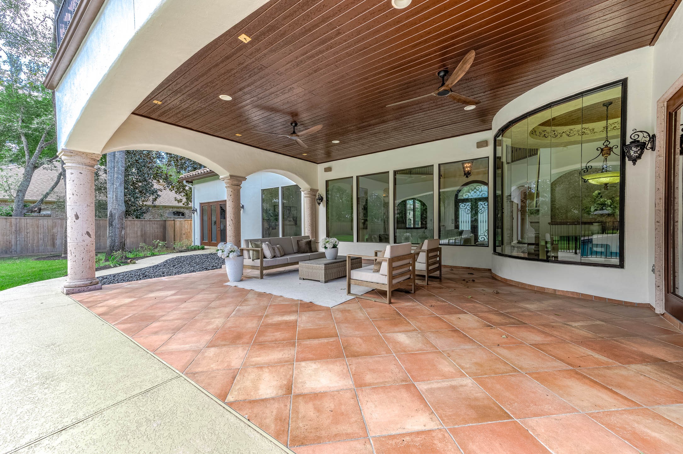 The covered patio features a stained wood ceiling and Cantera stone columns, extending the home's living space outdoors.
