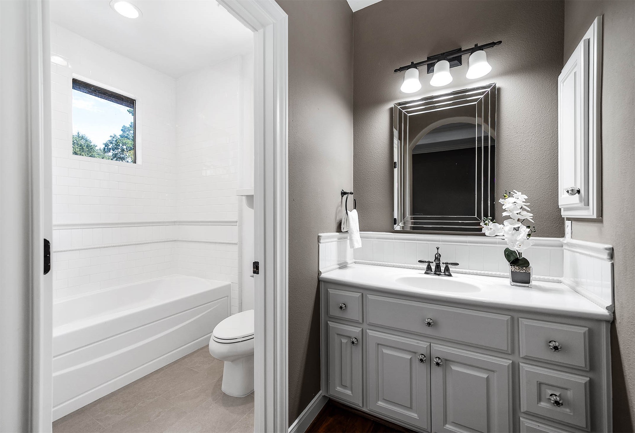 The ensuite bath features a single vanity and a tub/shower combination finished in fresh white tile.