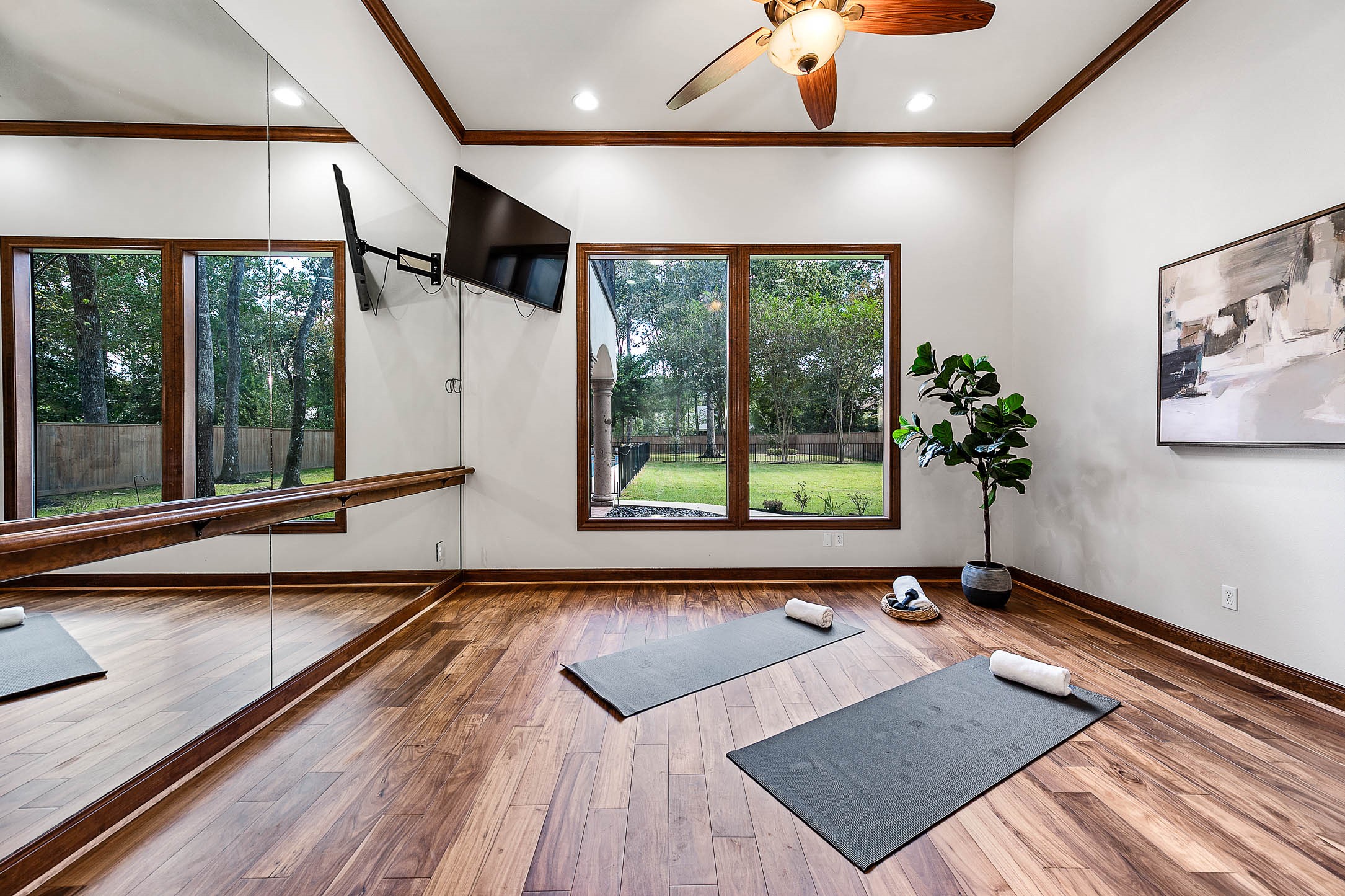 The flex room features hardwood floors, a full mirrored wall with a ballet barre, and views of the wooded backyard.