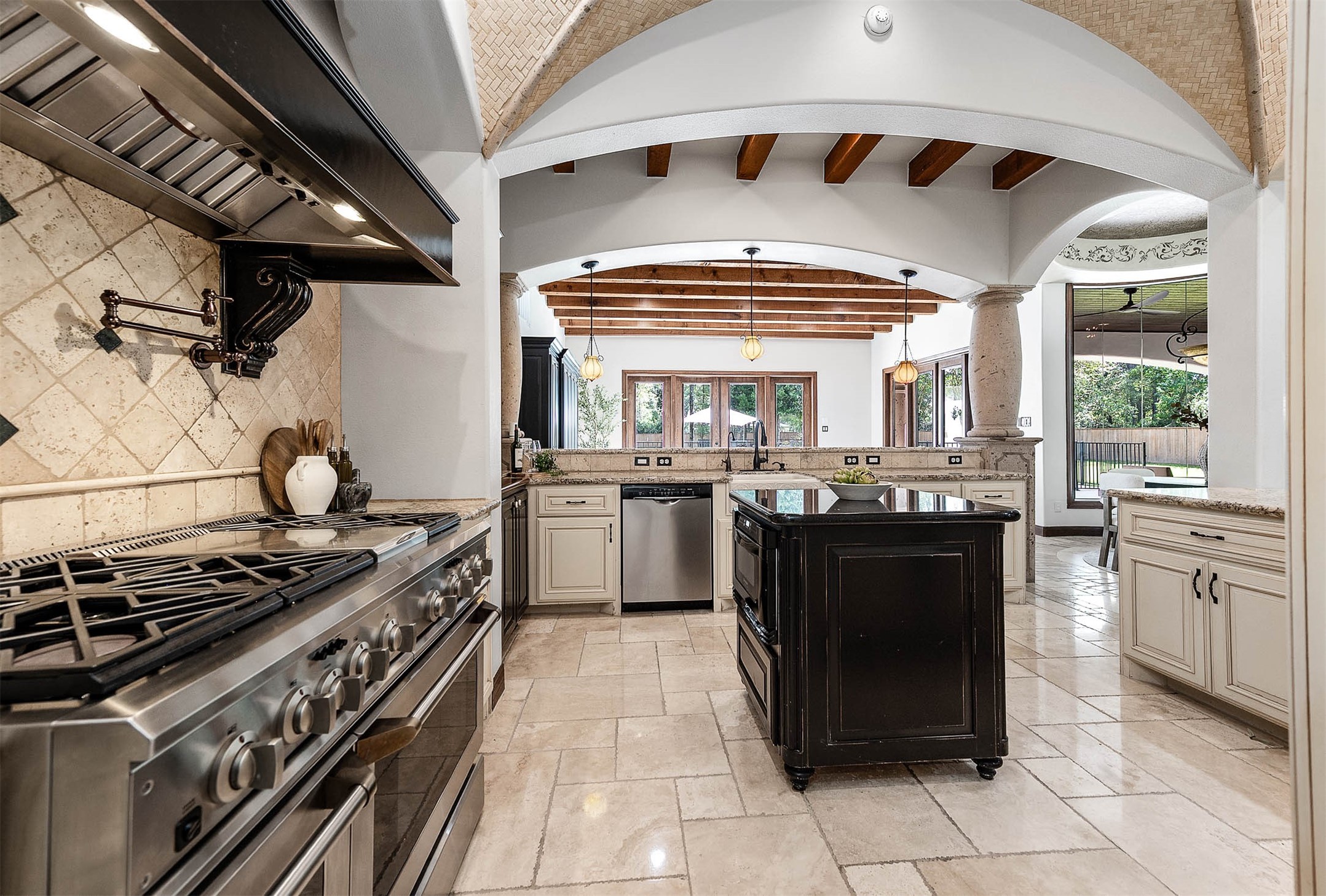 A gas range with double ovens, a pot filler, and a custom vent hood anchors the kitchen.