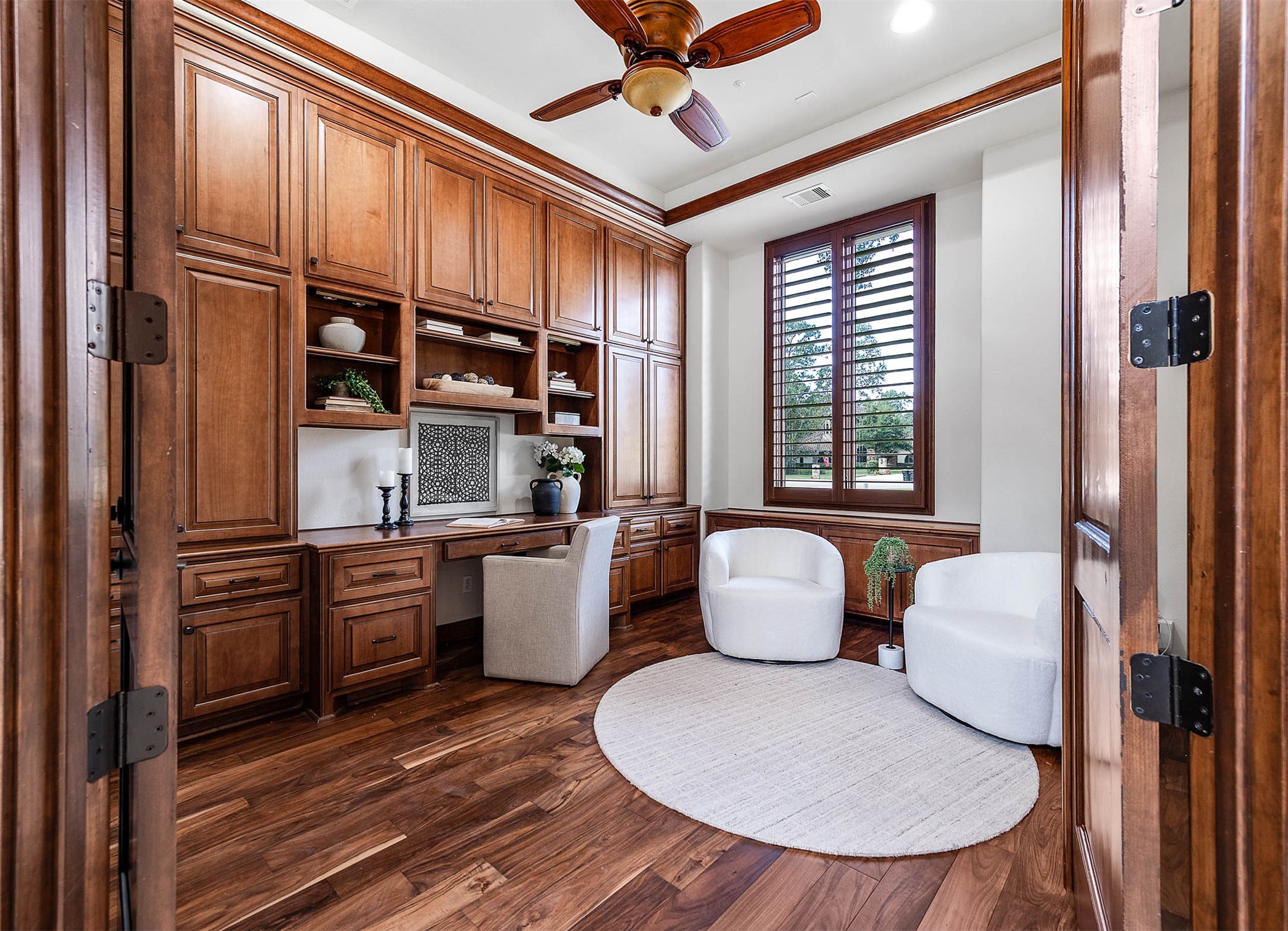 The home office off the front of the home features rich wood-paneled built-ins, a custom desk, and hardwood floors.