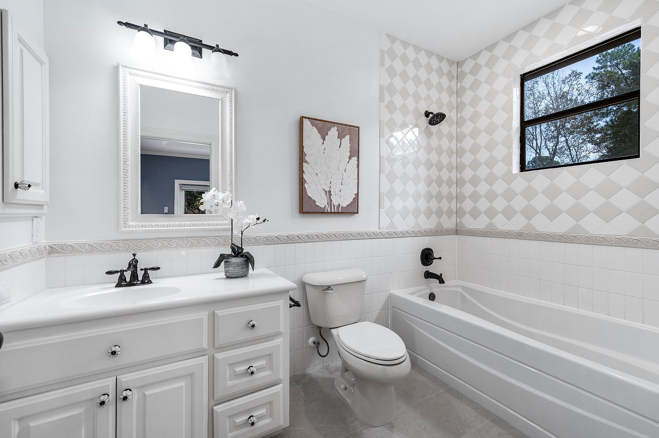 This secondary bath features new diamond-pattern tile, a single vanity, and a tub/shower combination.