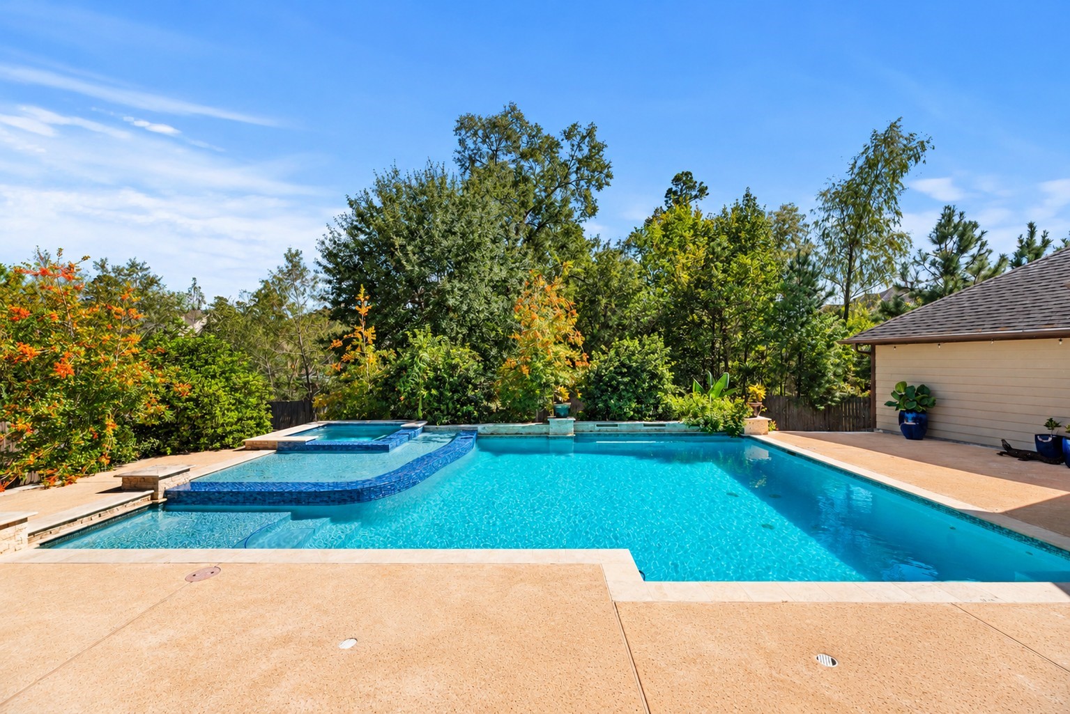 The sparkling resort-style pool with a raised spa, expansive decking, and lush, mature landscaping provides a beautiful, private setting.