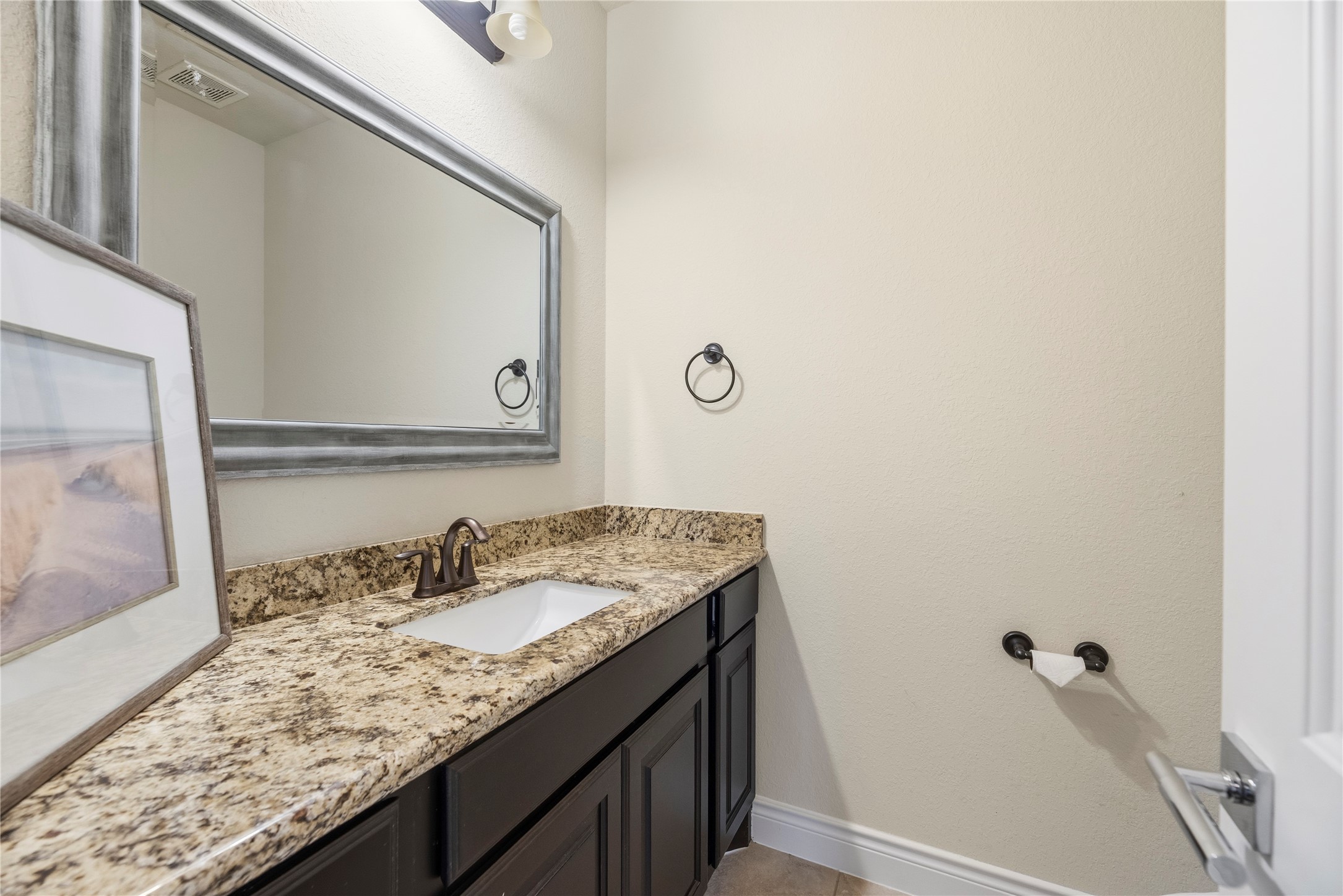 Convenient half bathroom with a granite vanity.