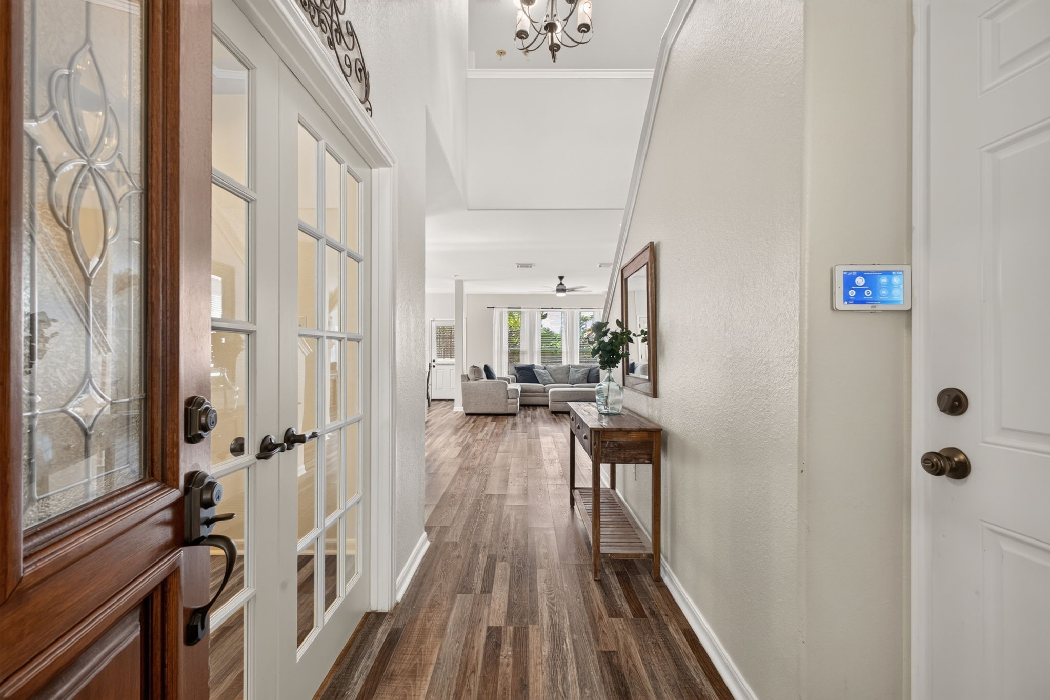 This inviting entryway features a glass-paneled front door and French doors leading to a study.