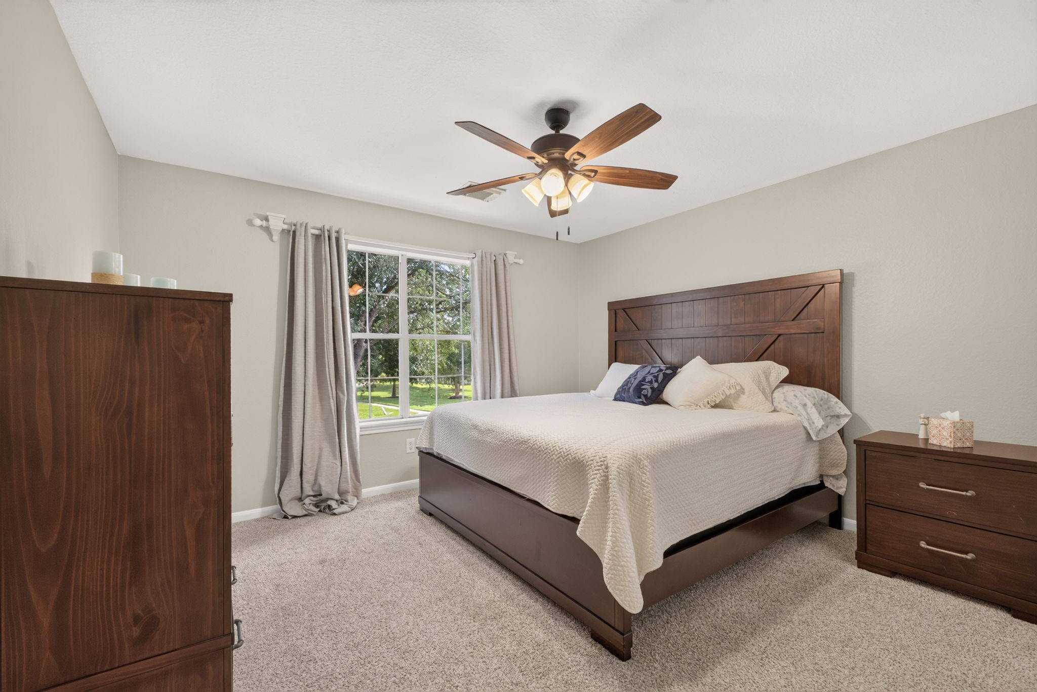 Secondary bedroom featuring a large window with a view, neutral walls, and carpeted flooring.