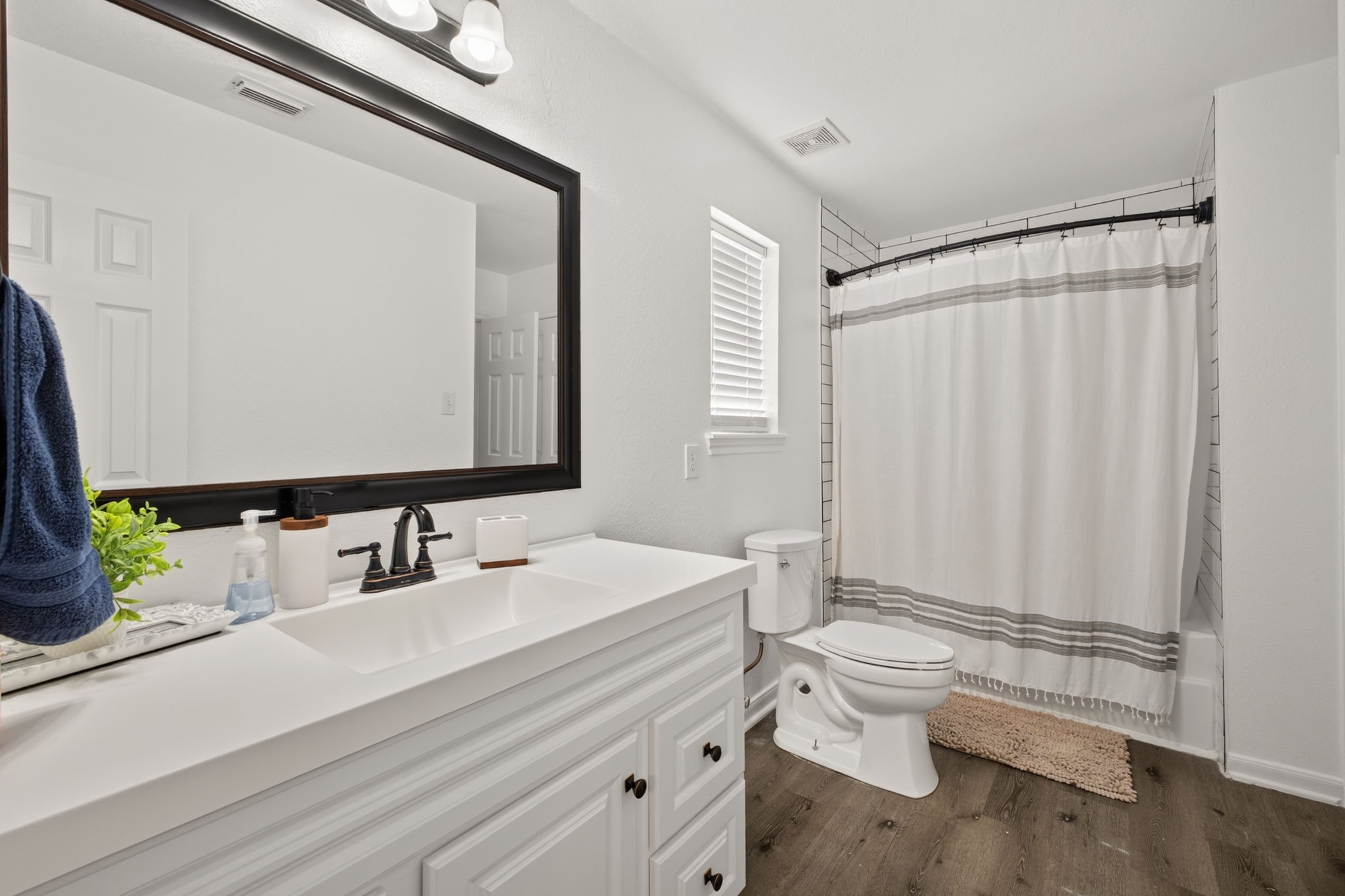 This updated bathroom features a modern design with a large vanity, dark-framed mirror, and sleek fixtures.