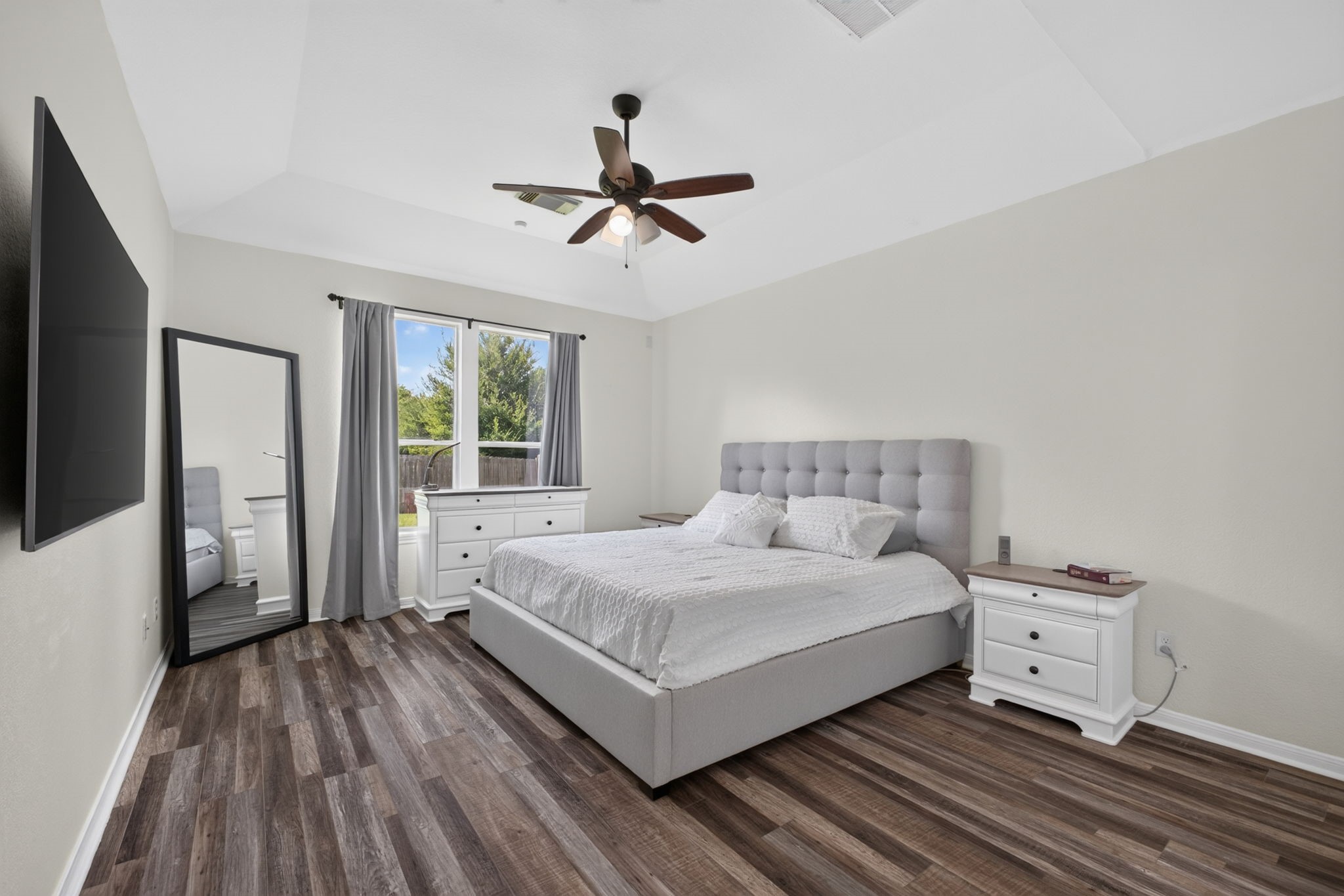 This spacious primary bedroom features a vaulted ceiling and large windows with natural light.