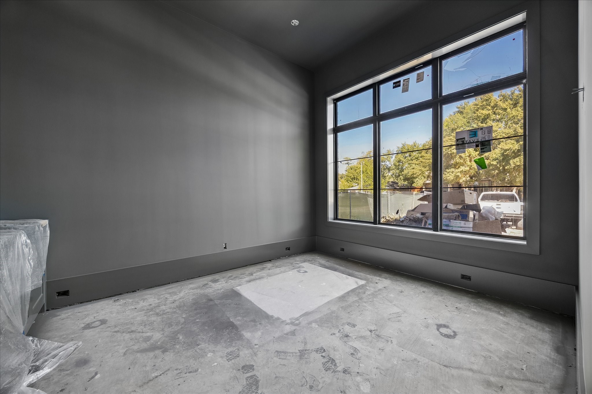 Contrasting dark paint distinguishes the dedicated study from the Alabaster main living areas. A large front window and recessed ceiling add light and architectural definition. Builder dimensions identify an 11 x 14 study; flooring and final fixtures remain in progress.