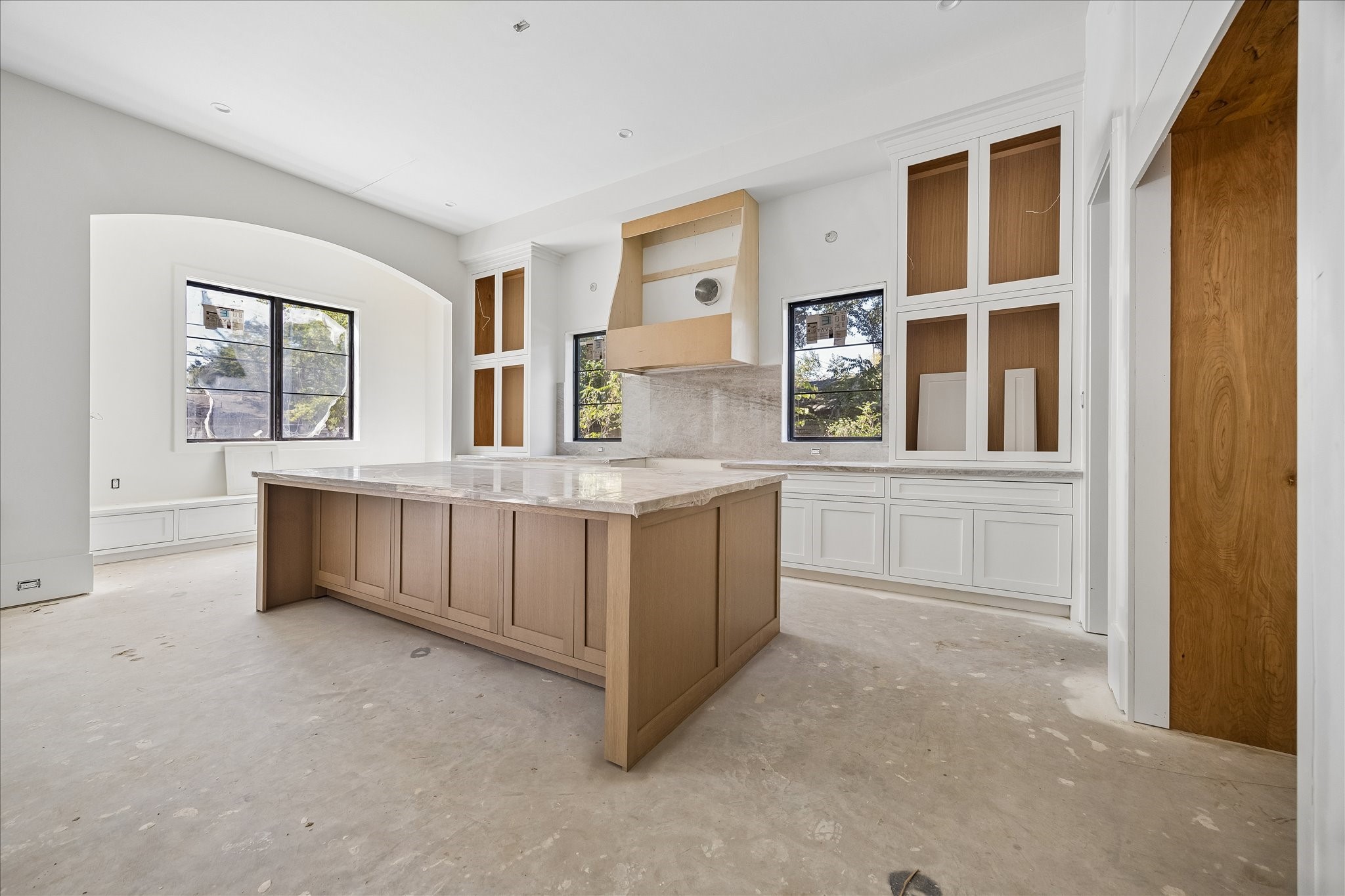 Tall cabinet towers and lower storage frame the kitchen work area, with 2 windows bringing light to the counters. The planned Thermador package includes a 48 inch range, 54 inch refrigerator and 2 dishwashers. Appliances and final cabinet fittings remain in progress.