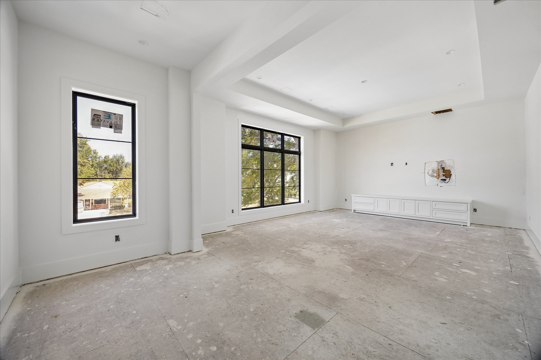 Built in lower cabinetry provides storage along one wall of this upper level room, leaving the center open for flexible use. A broad window, recessed ceiling and substantial trim give the space definition. Flooring, lighting and final fittings remain in progress.