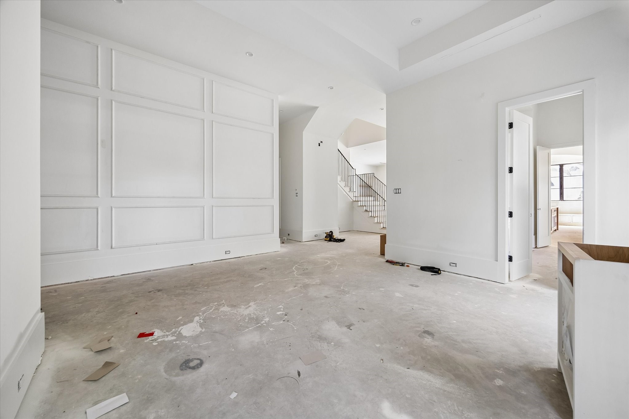 Rectangular wall molding gives the dining room a defined architectural backdrop. A wide opening leads toward the stair hall and adjoining spaces. Builder specifications call for 12 inch downstairs baseboards, adding scale to the trim package beneath the tall ceilings.