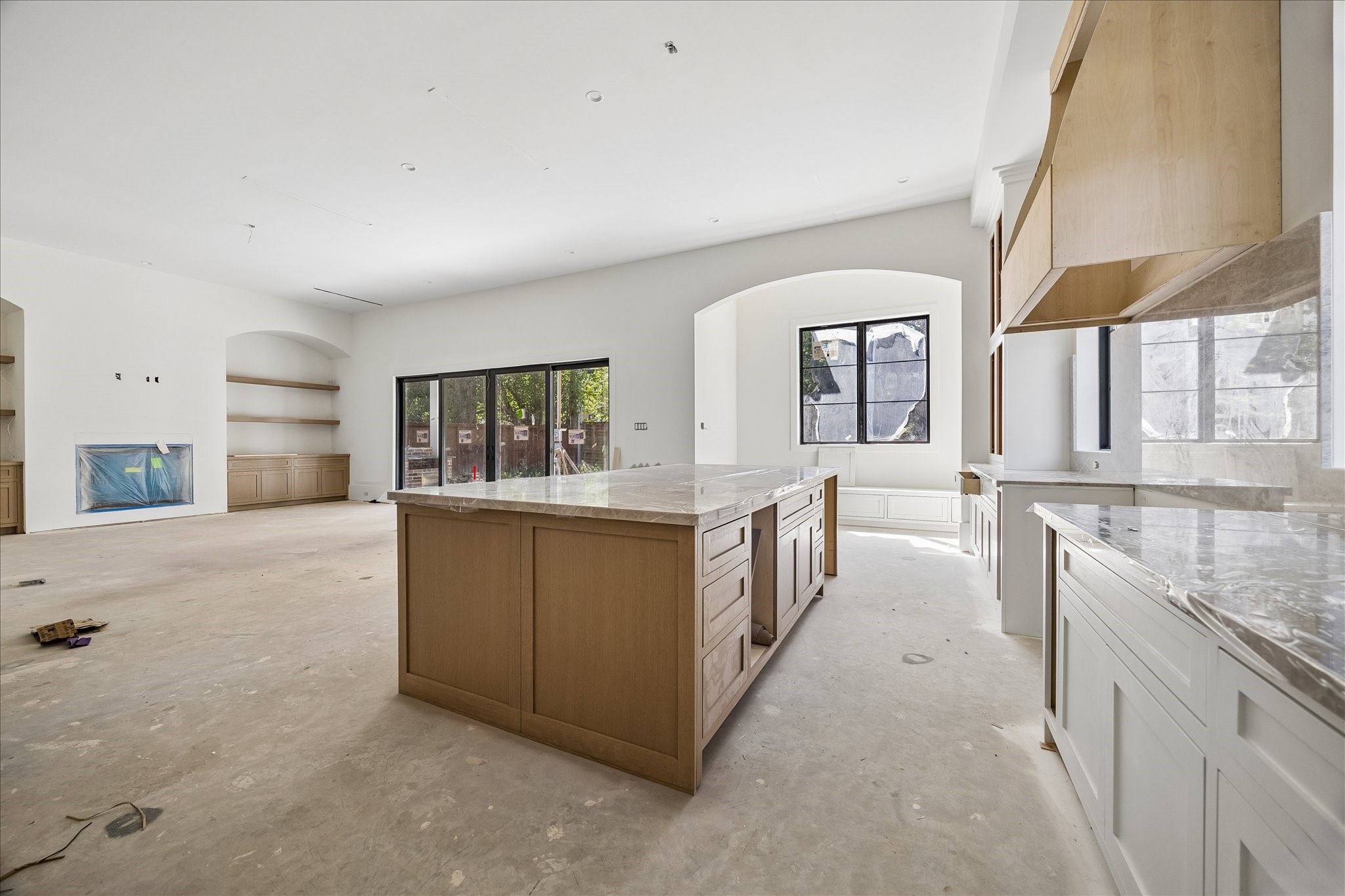 Breakfast seating runs only along the back wall beneath an arched window, preserving open floor space and an easy route to the rear doors. The built in bench connects everyday dining with the island kitchen, living room and covered outdoor area.