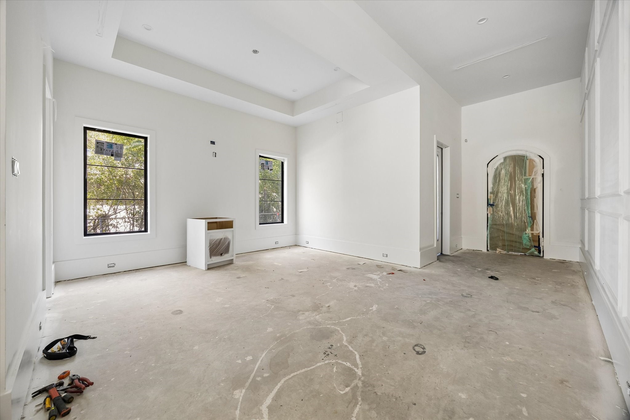 Tray ceiling detail frames the dining room beside the arched front entry, while two tall windows bring daylight across the room. Alabaster was selected for the main walls and ceilings, providing a light backdrop for the architectural trim and planned European oak flooring.