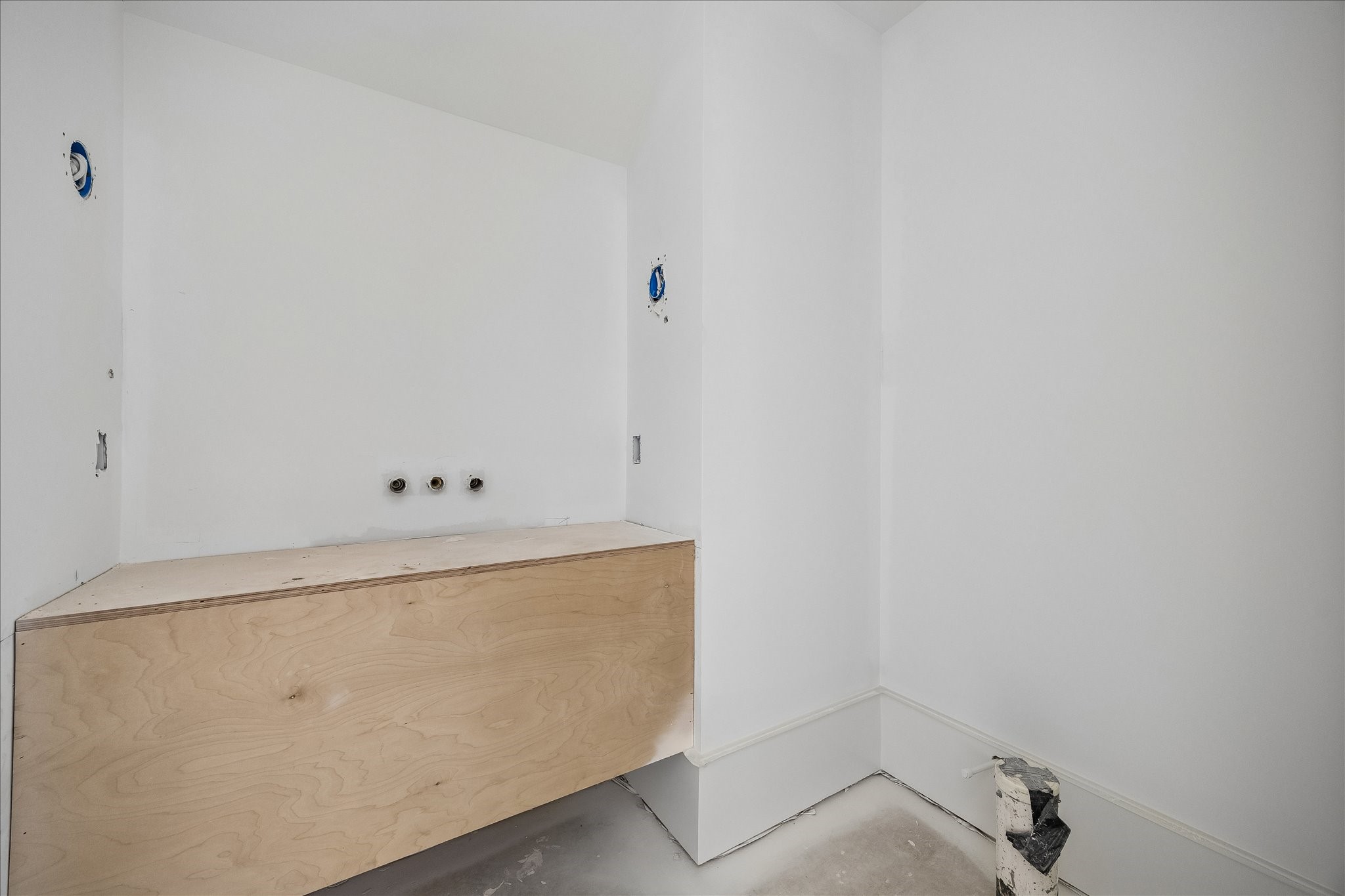 Floating vanity cabinetry leaves the floor beneath open and gives this bath a simple profile. Wall plumbing rough ins and an adjoining recess show the layout before the basin, counter, mirror and fittings are installed. The photo records the current construction stage.