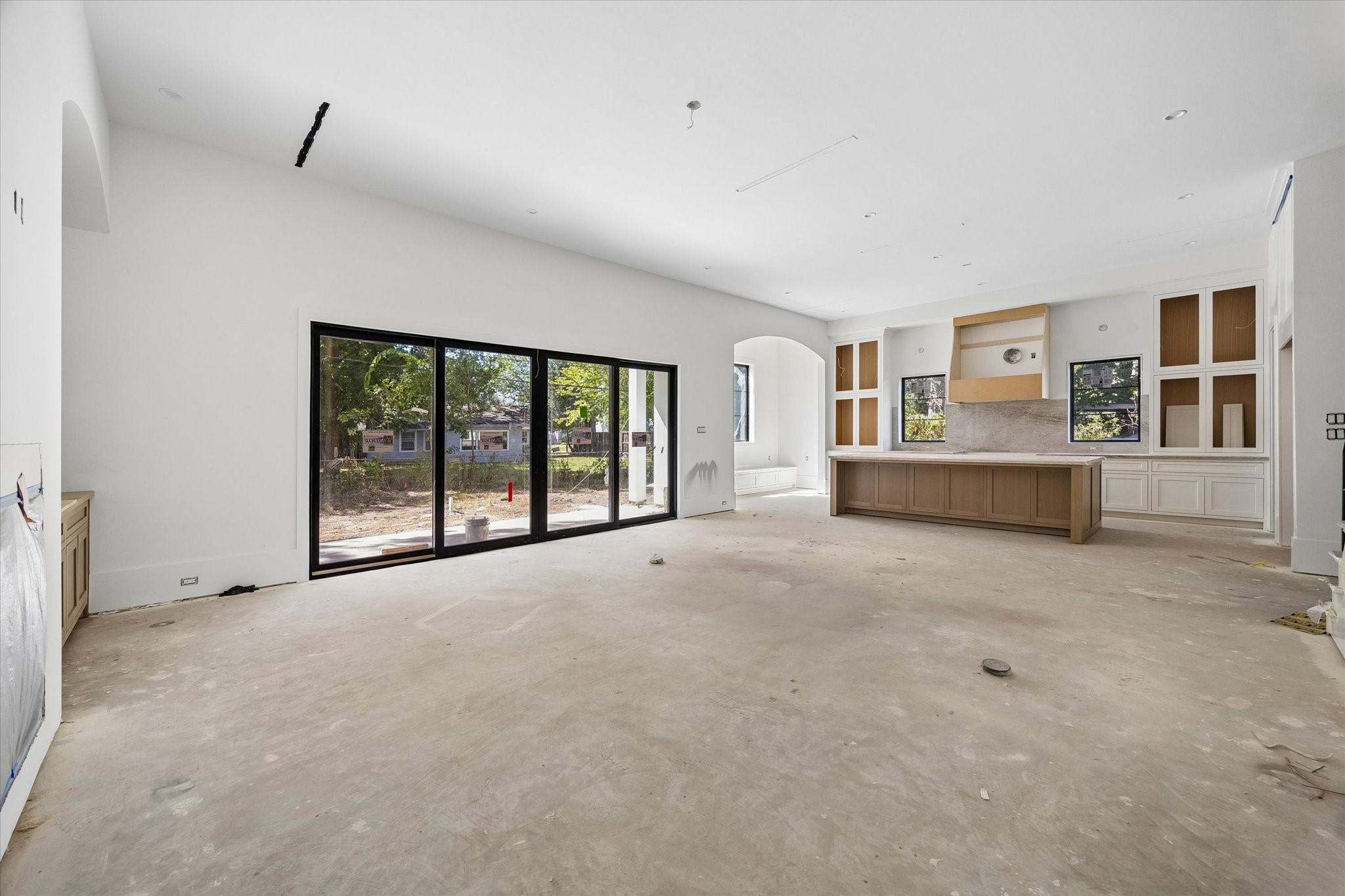 Broad rear glazing links the open living area, island kitchen and breakfast nook with the backyard. Linear air vents keep the ceiling lines restrained. Builder specifications call for 12 foot downstairs ceilings, reinforcing the scale of these connected gathering spaces.