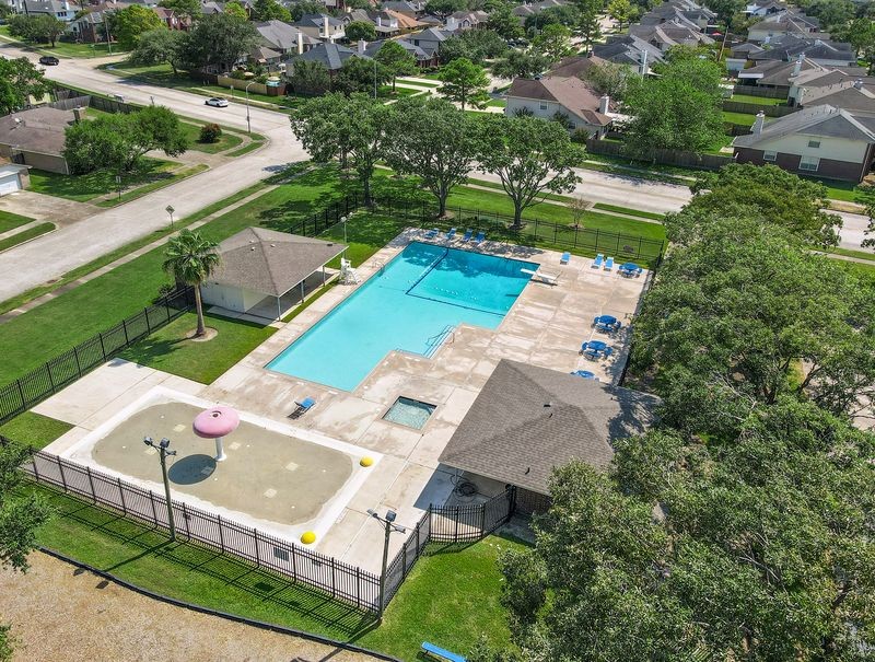 Another View of the Neighborhood Pool Area Featuring a Spacious Swimming Pool, Separate Splash Pad, Lounge Chairs, and Shaded Pavilion.