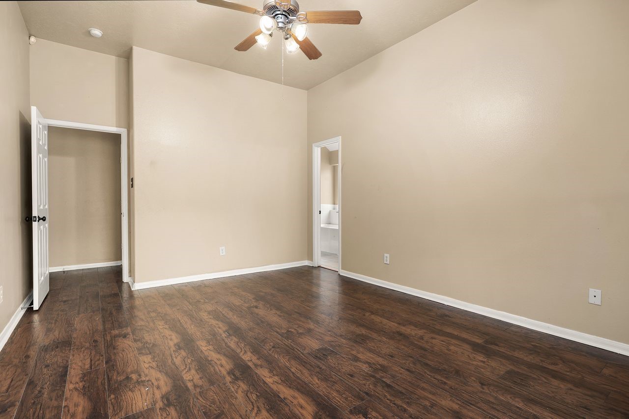 Another View of the Generous Primary Suite Highlighting the Beautiful Wood-Look Flooring, and Convenient Access to the Private Bath.