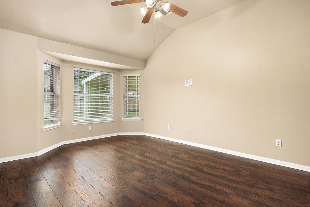 Spacious Primary Bedroom Features Beautiful Wood-Look Flooring, High Ceiling, and a Charming Bay Window That Brings in Plenty of Natural Light.