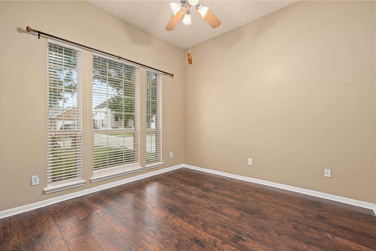 Another Nicely Sized Secondary Bedroom with Beautiful Wood-Look Flooring, Ceiling Fan, and Large Windows Overlooking the Front Yard.