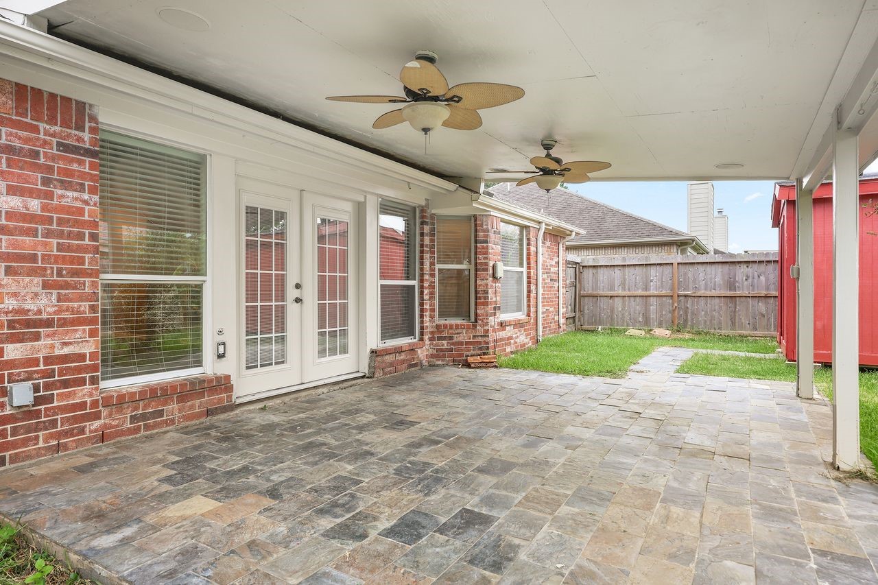 Expansive Covered Patio with Slate Flooring and Two Ceiling Fans, Perfect for Outdoor Relaxation and Entertaining!