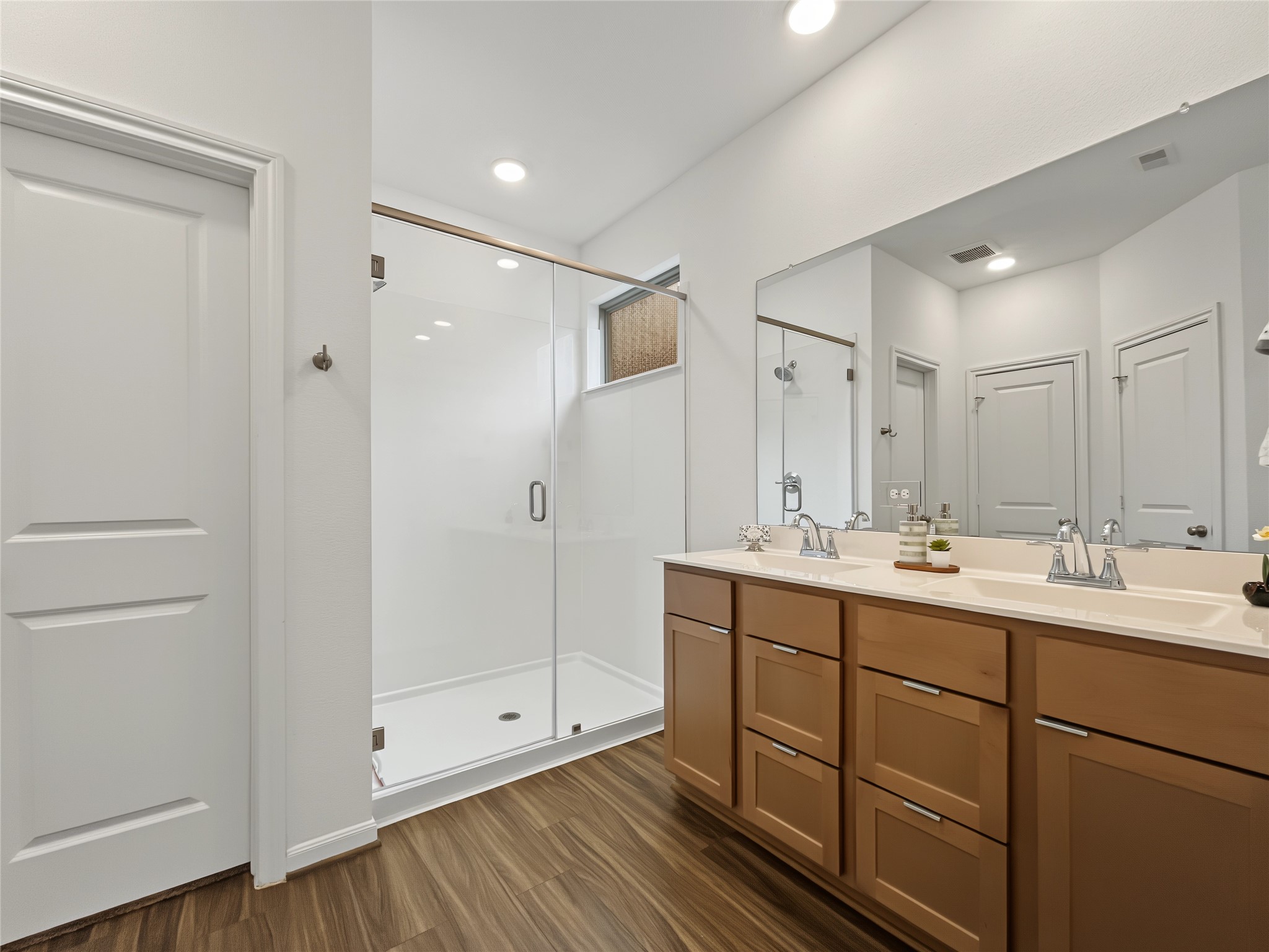 View of the shower and the vanity with two sinks in the primary bathroom.