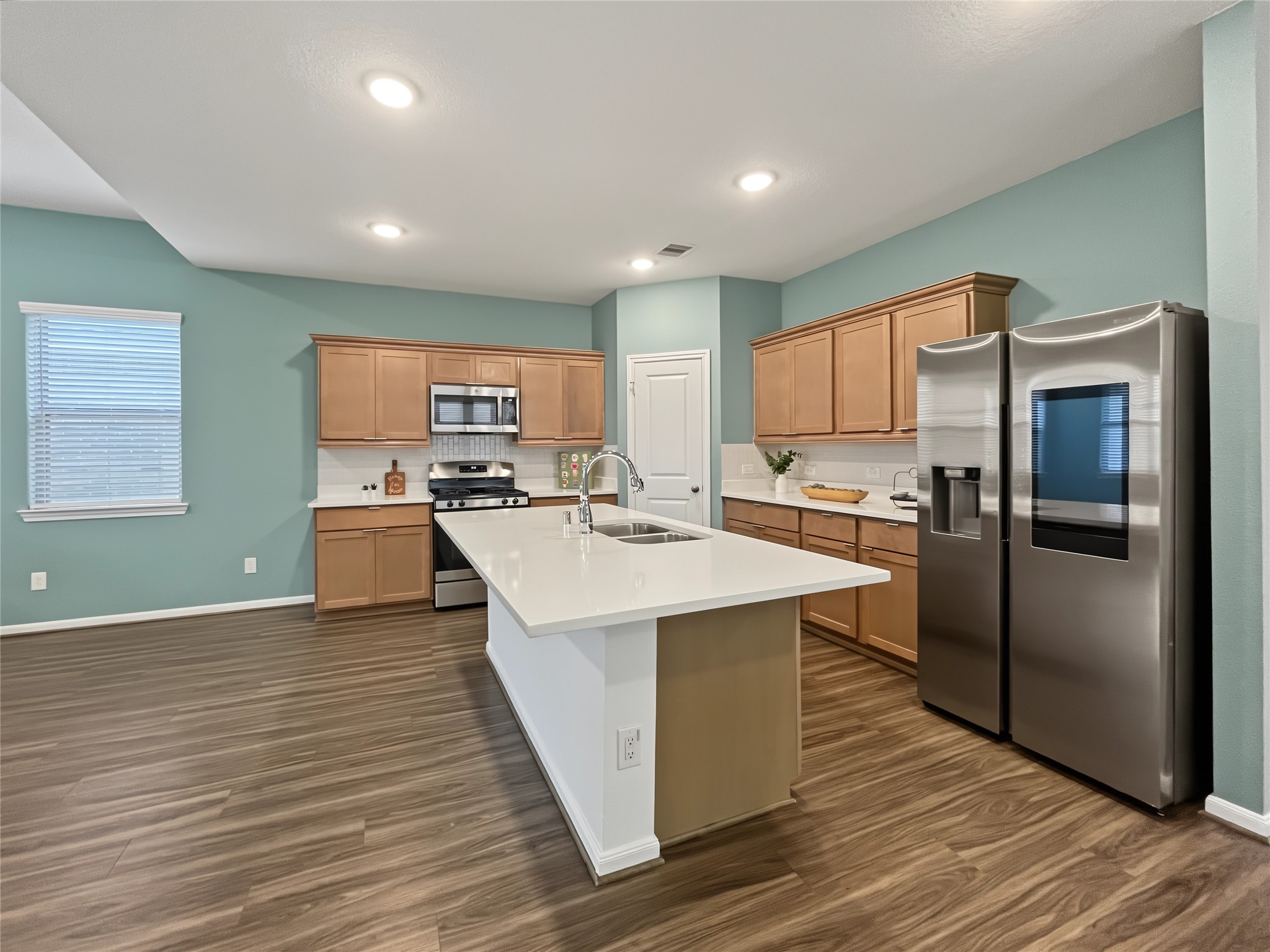 The kitchen is loaded with stainless steel appliances and quartz countertops.