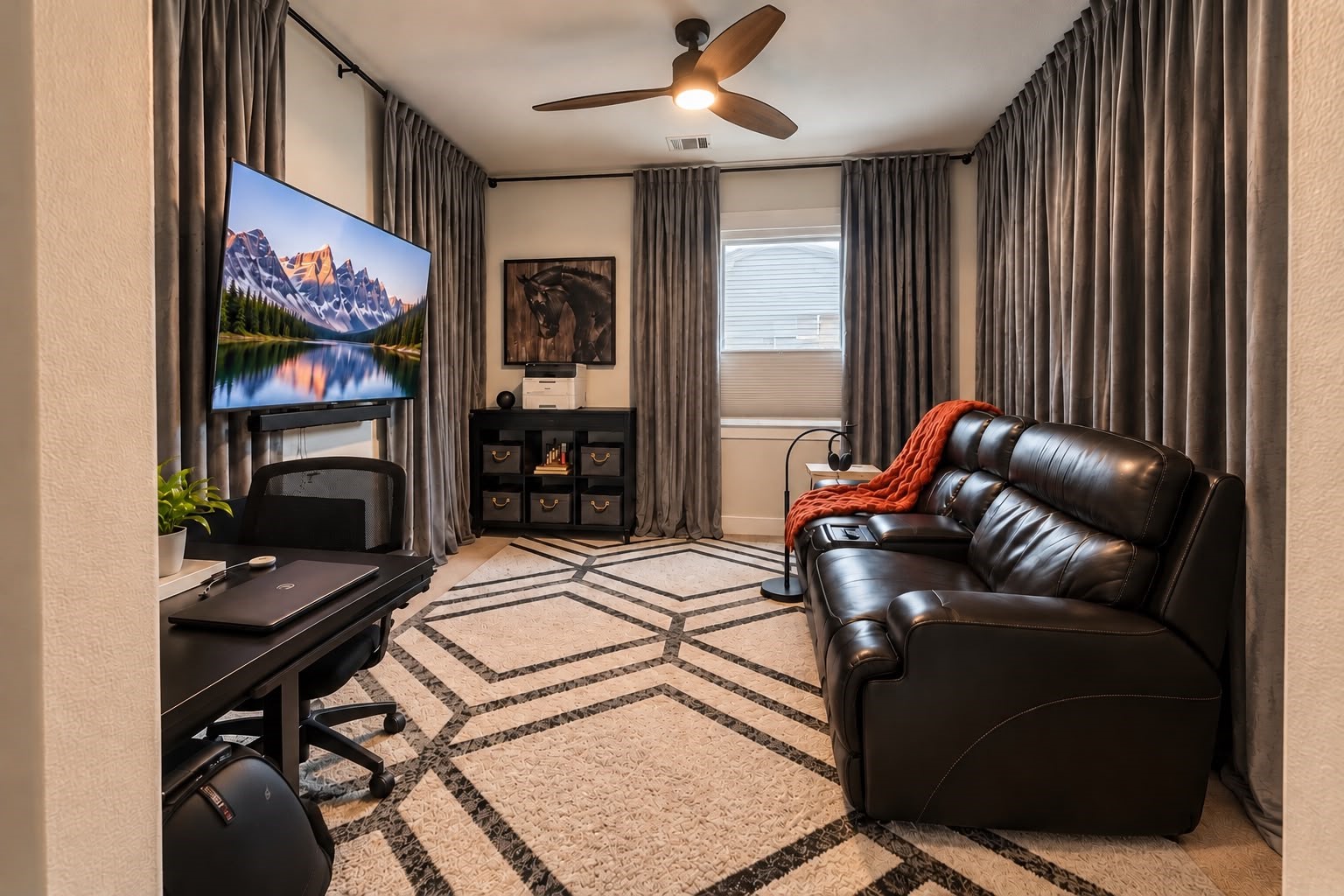 Private media room featuring a large television, comfortable leather seating, full-length curtains, and a geometric-patterned area rug.