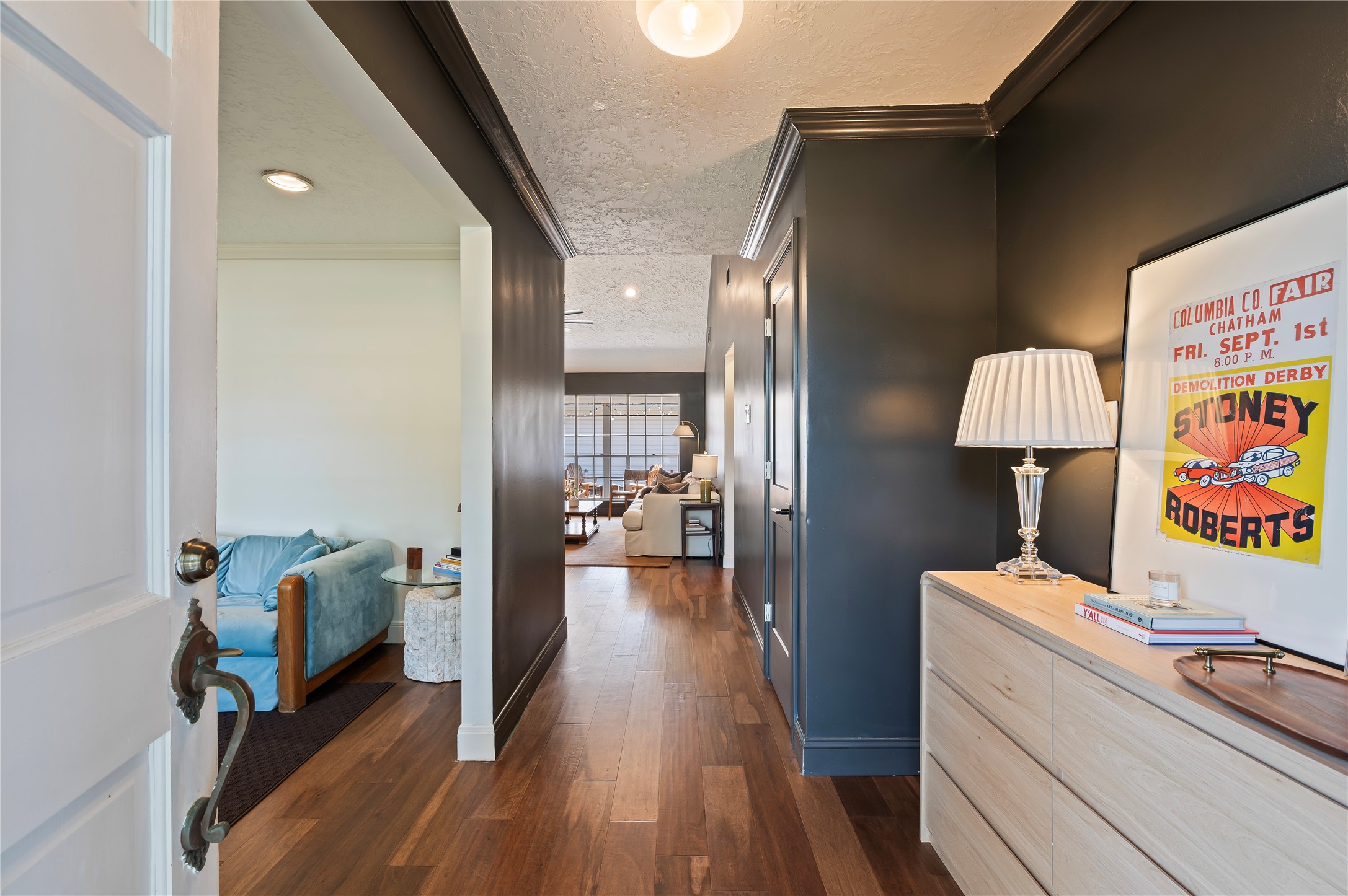 Front door opens up to the entryway with wood like flooring and views into the back of the home.