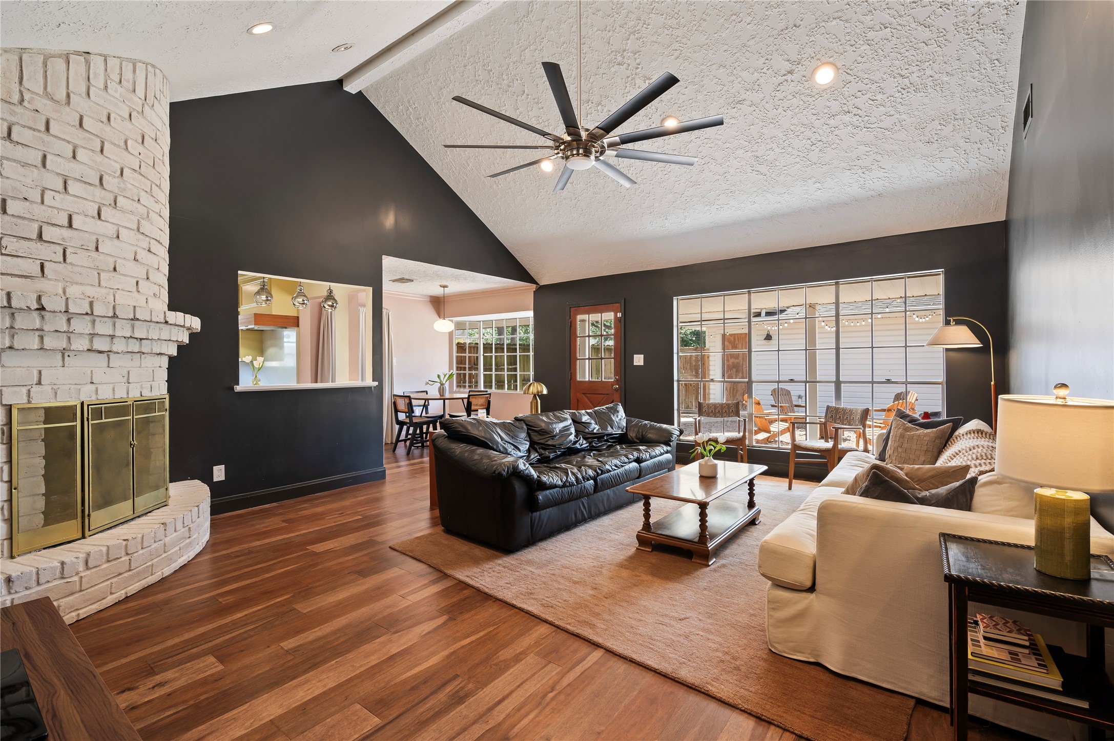 Very spacious living room with high ceilings, oversized stainless ceiling fan and brick fireplace.