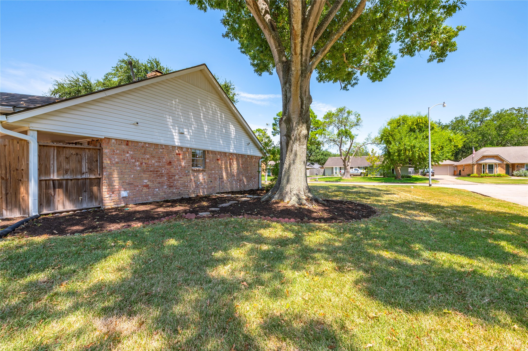 Additional side yard with landscaping beds and mature tree.