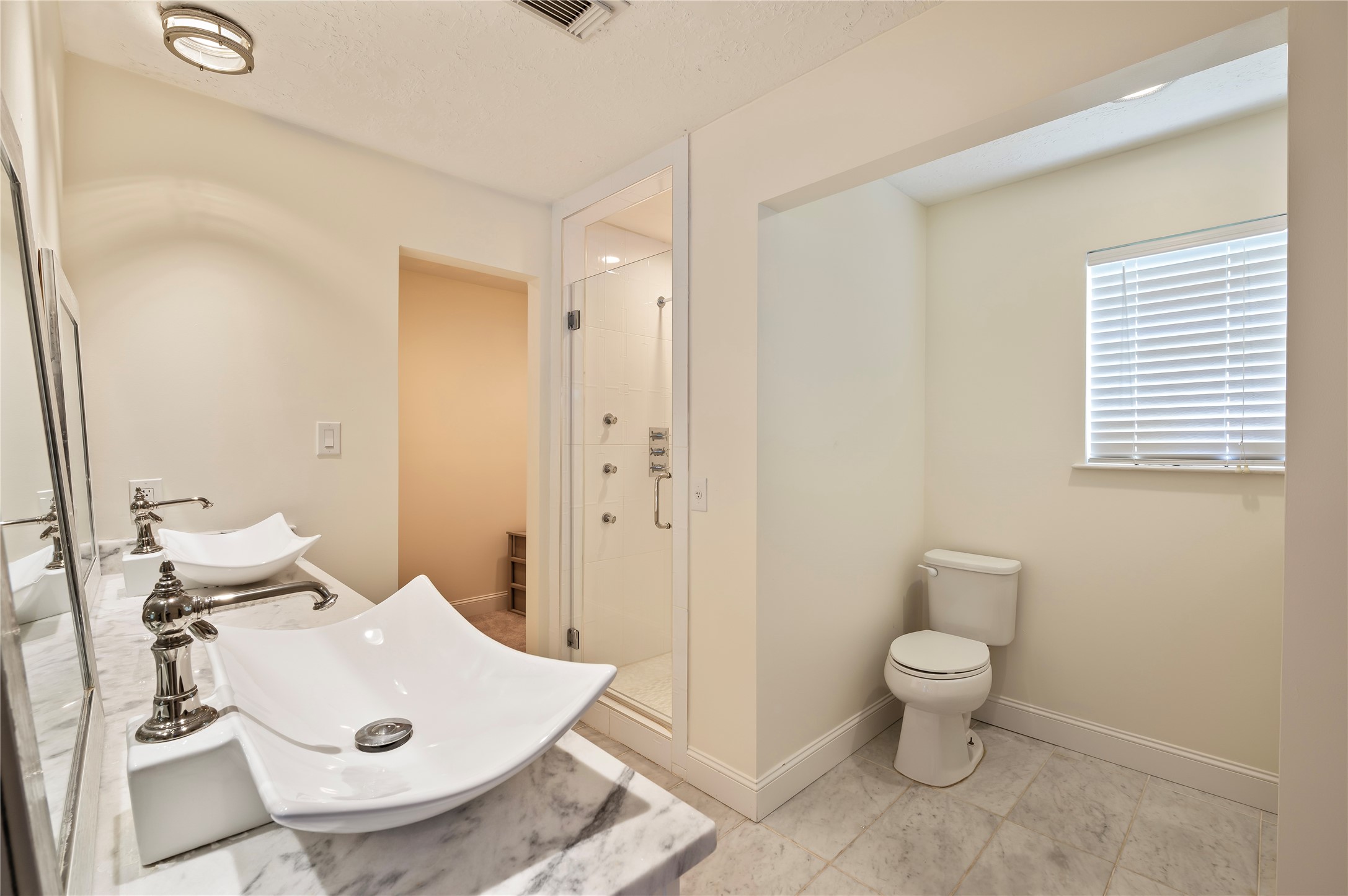 Another view of the large primary bath with his/her sinks and additional vanity to the right.