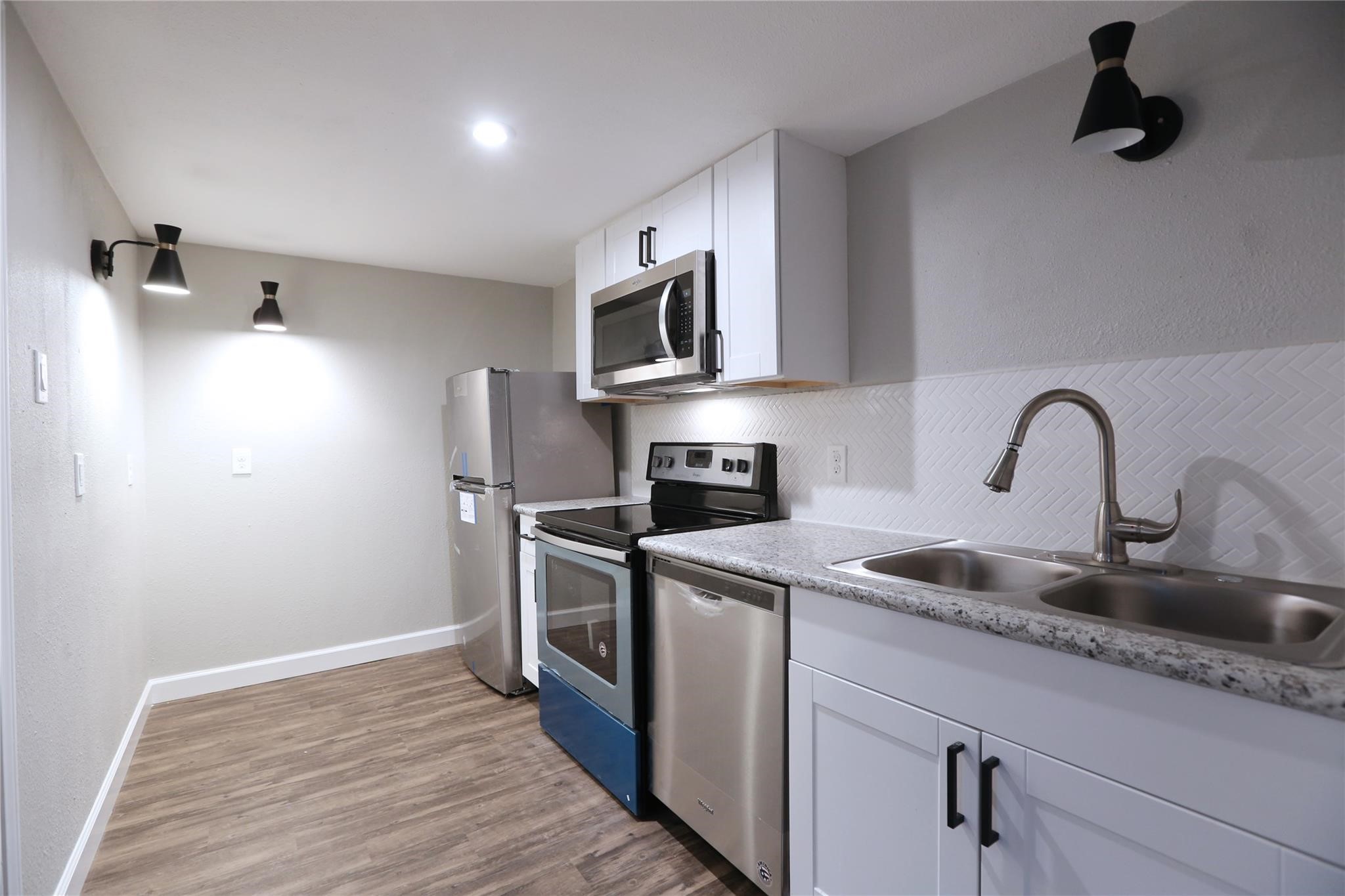 Open space between the living room and kitchen which comes with stove, refrigerator, oven, microwave and a stacked washer & dryer on the side.