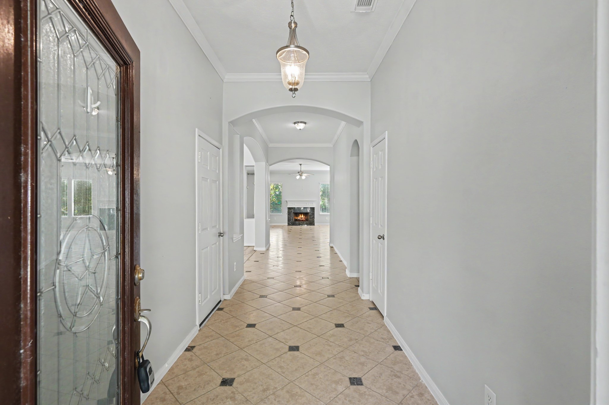 Inviting foyer with decorative tile flooring, crown molding, pendant lighting and elegant archways leading into the spacious living area.