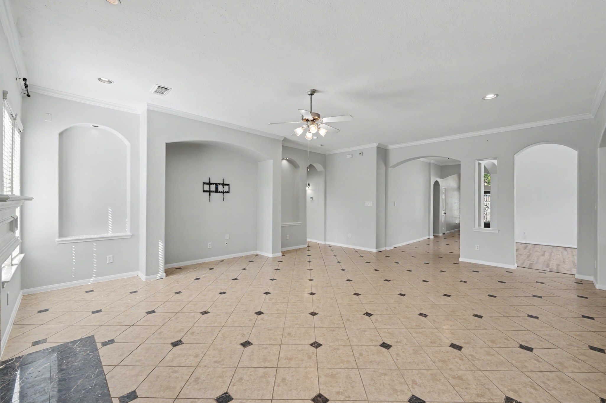 Spacious family room featuring decorative tile flooring, crown molding, elegant archways and an open layout ideal for everyday living and entertaining.