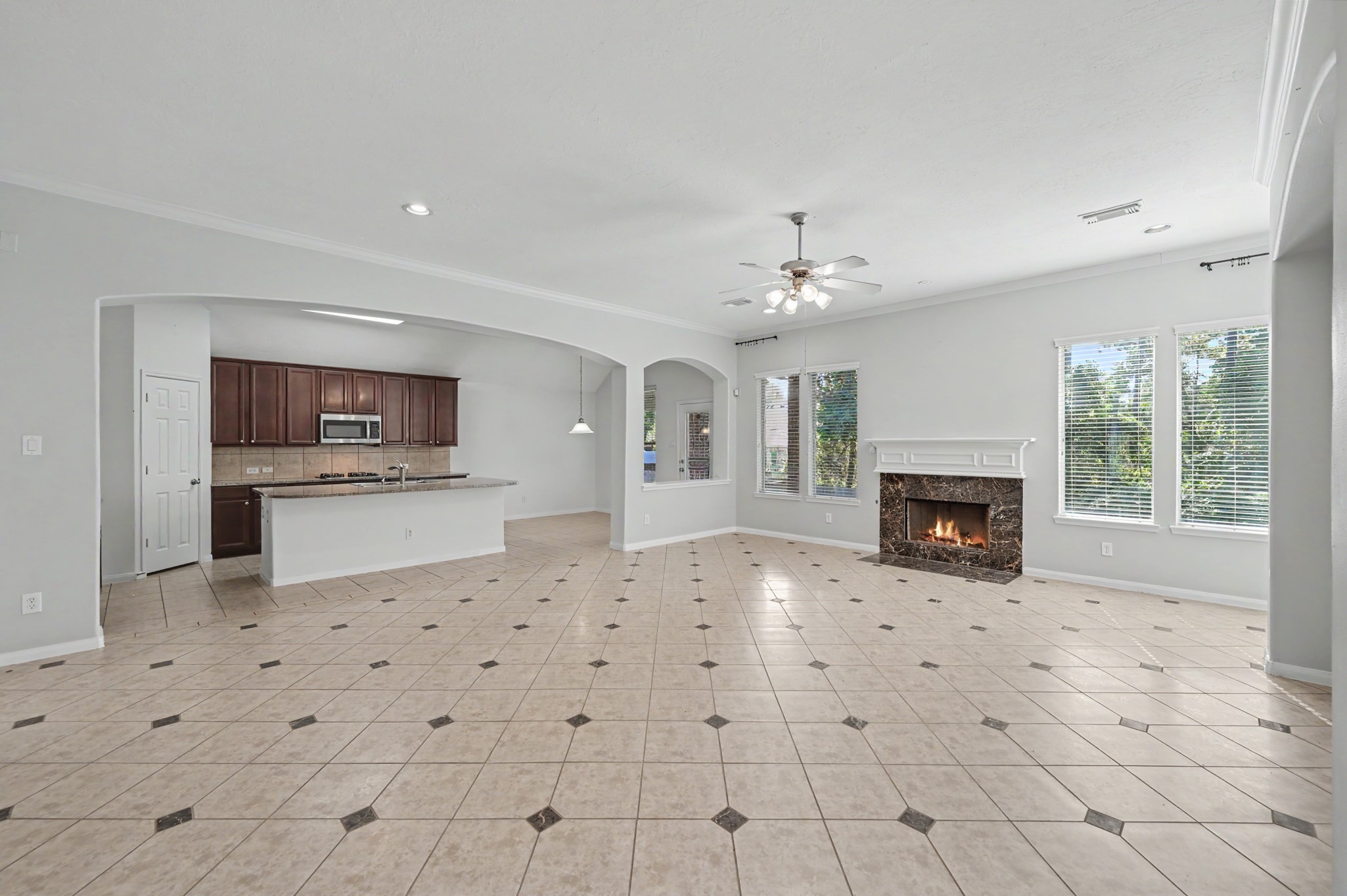 Expansive open-concept family room with cozy fireplace, decorative tile flooring and seamless flow into the spacious island kitchen and breakfast area.