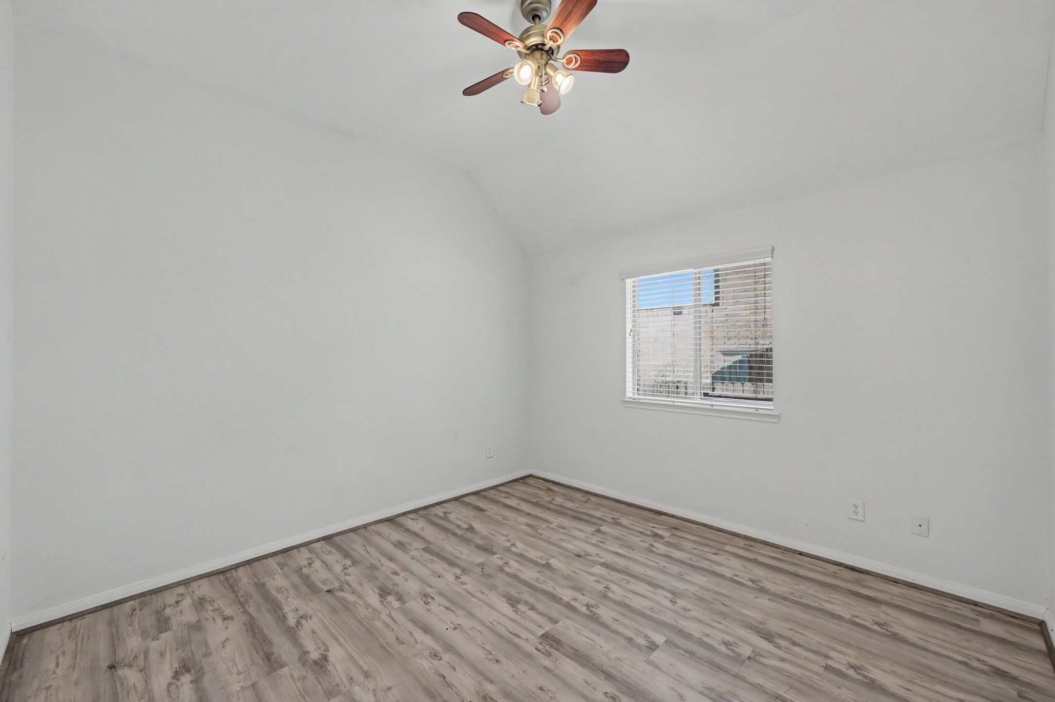 Generously sized secondary bedroom featuring wood-look flooring, ceiling fan and natural light.