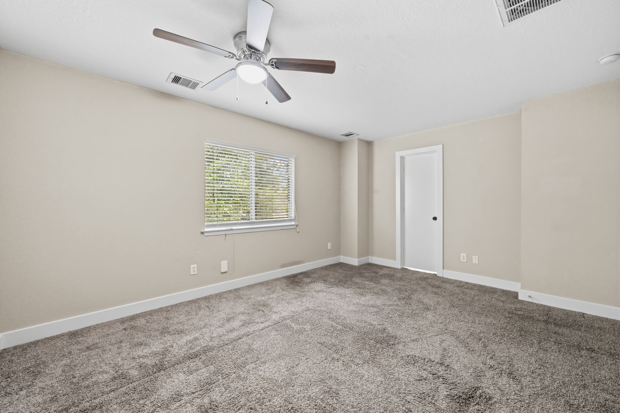 Spacious primary bedroom with door to the ensuite bathroom