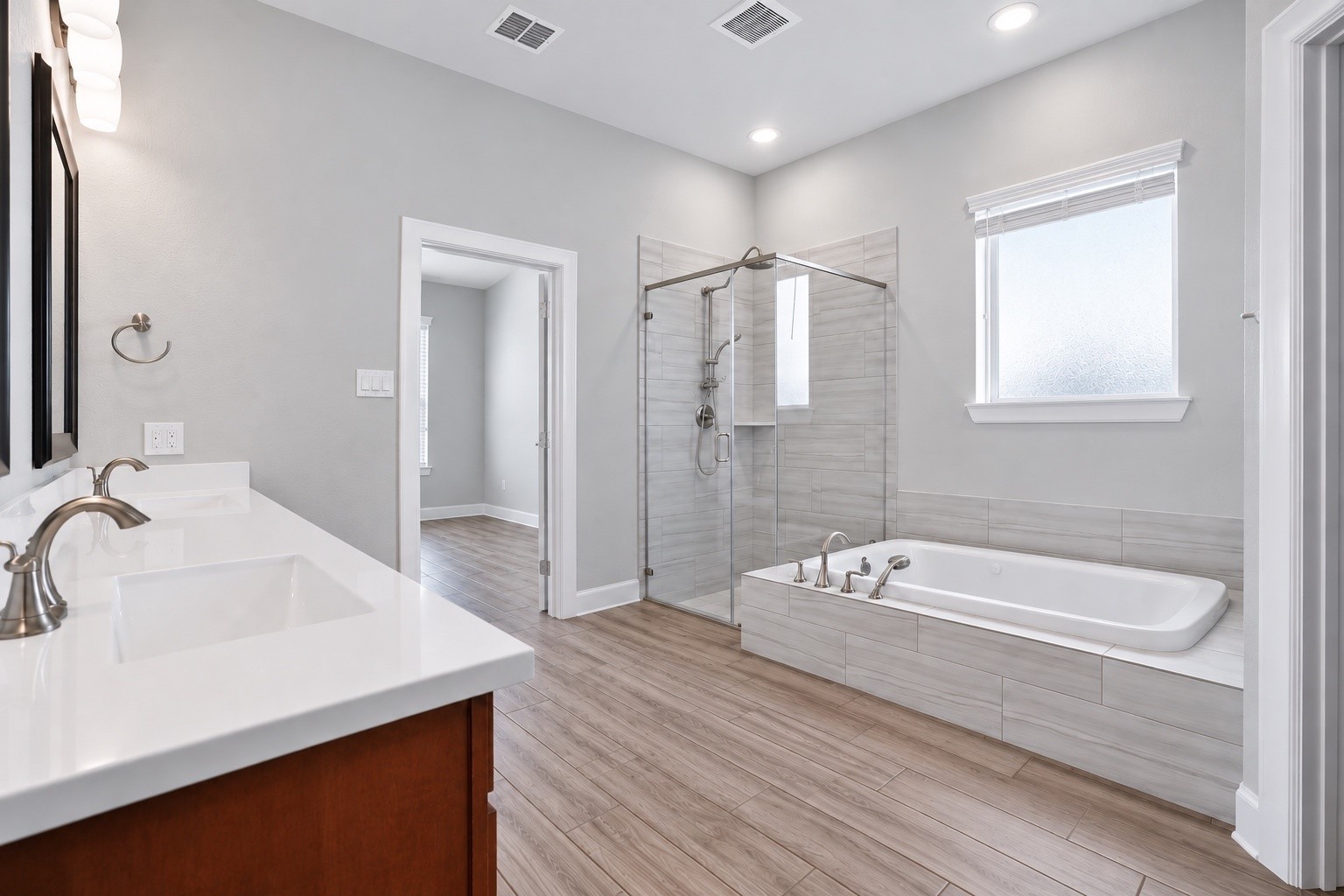 Spacious primary bathroom featuring dual sinks, a separate walk-in shower, and a separate soaking tub.