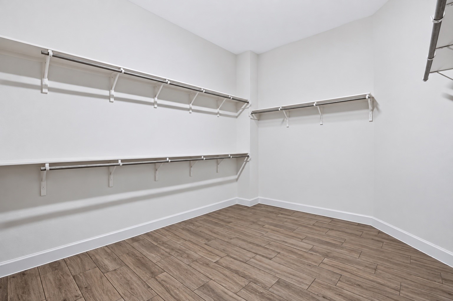 Large walk-in primary closet with plenty of shelving and hanging space for storage and organization.