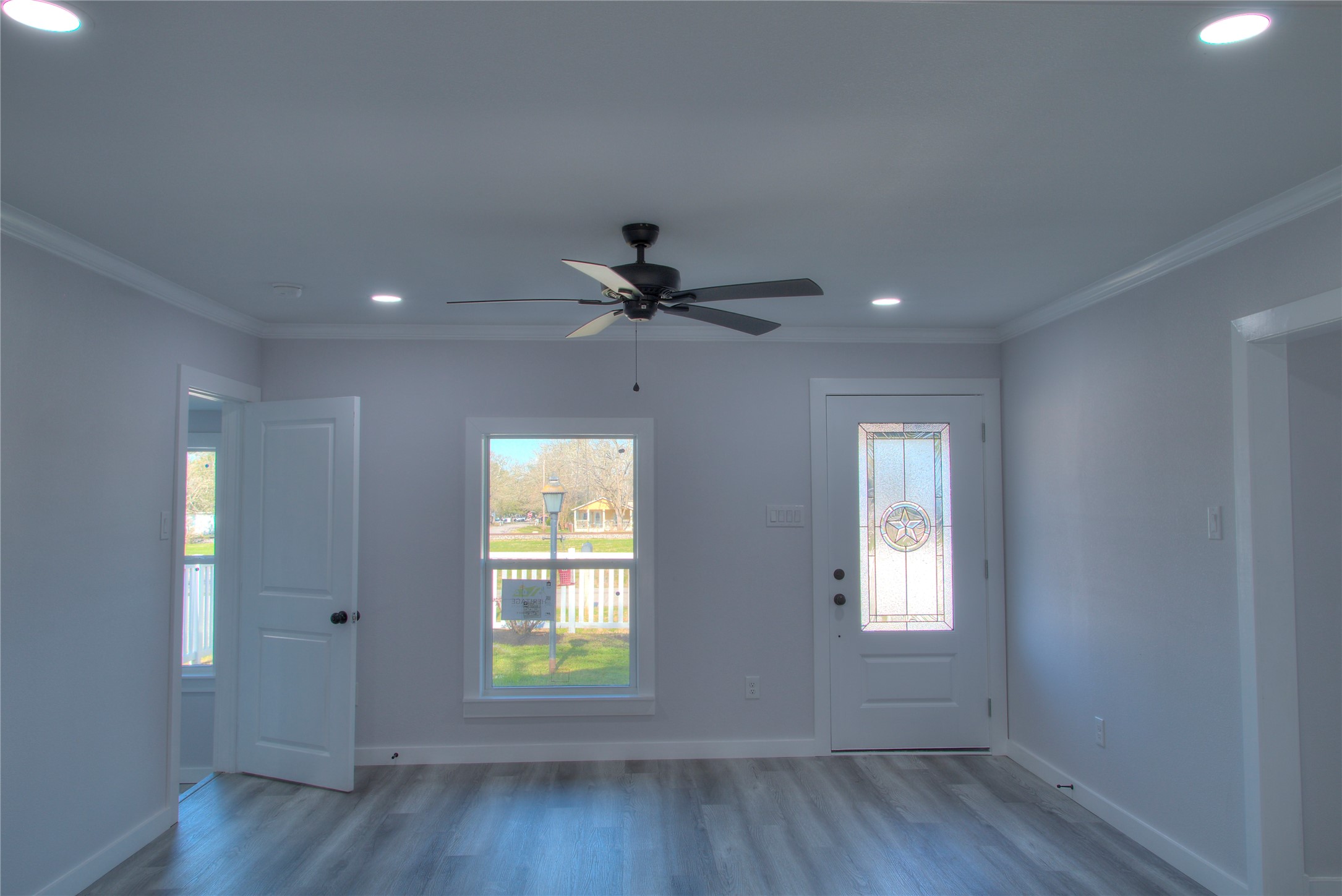 Inviting family room with a ceiling fan, modern canister lighting, and a stunning glass front door. Inviting family room with a ceiling fan, modern canister lighting, and a stunning glass front door.