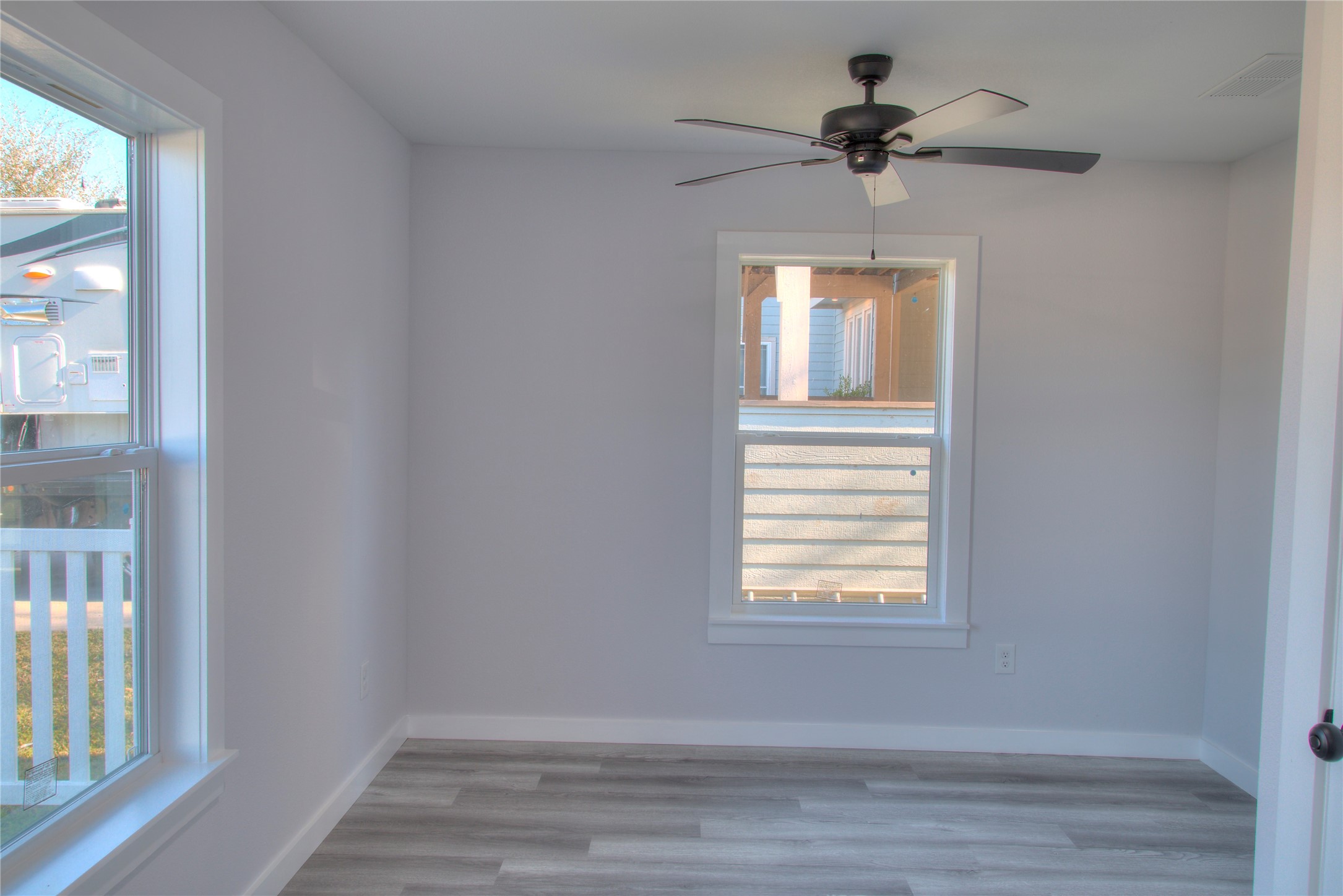 Cozy secondary bedroom featuring ample natural light and a sleek ceiling fan. Perfect for guests or a home office.