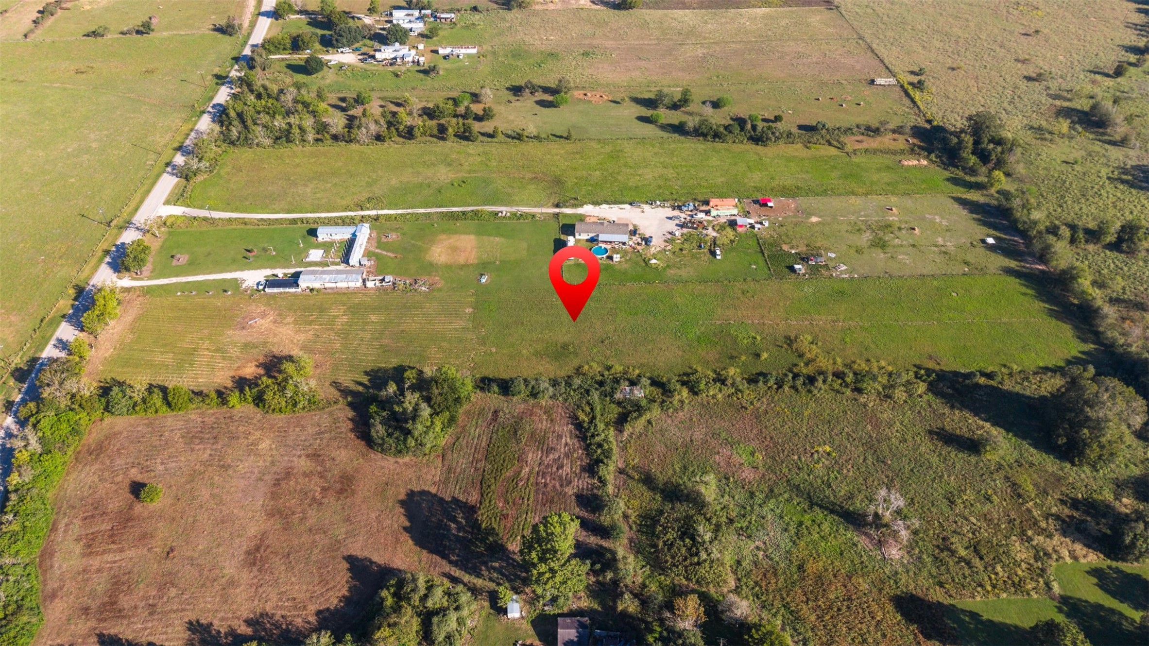 North-facing aerial offering an overhead perspective of the property's position along FM 1887, with neighboring improvements providing a sense of the area's rural character and surrounding land use.