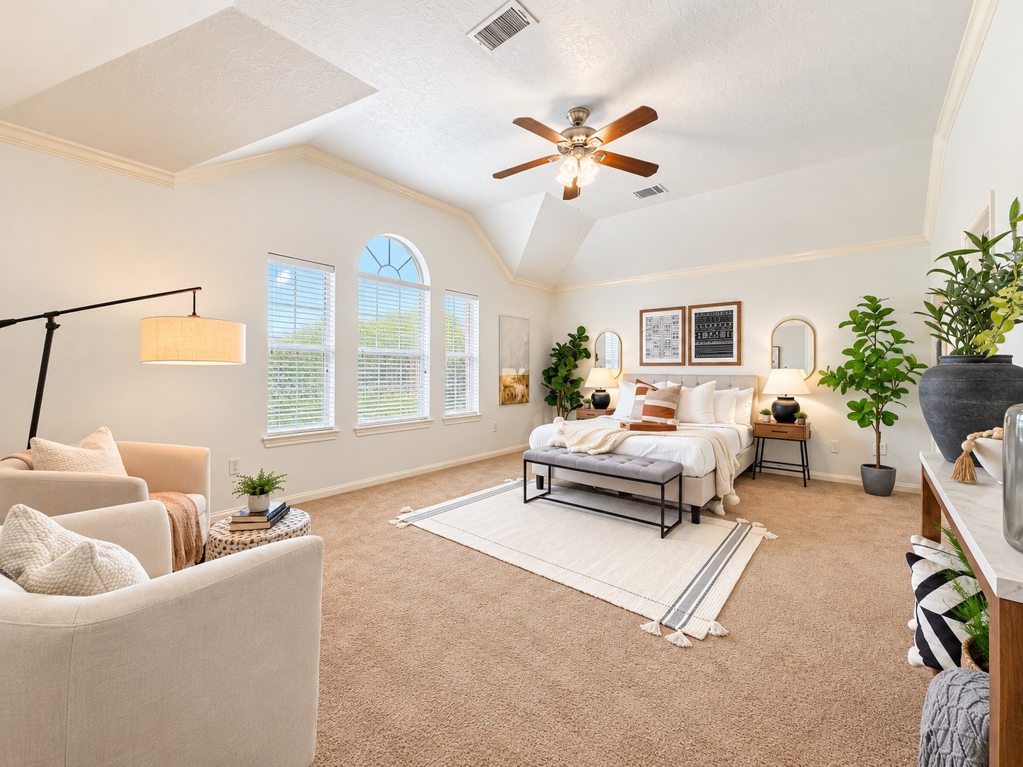 Spacious primary bedroom with abundant natural light, cozy seating area, and elegant decor for ultimate relaxation.