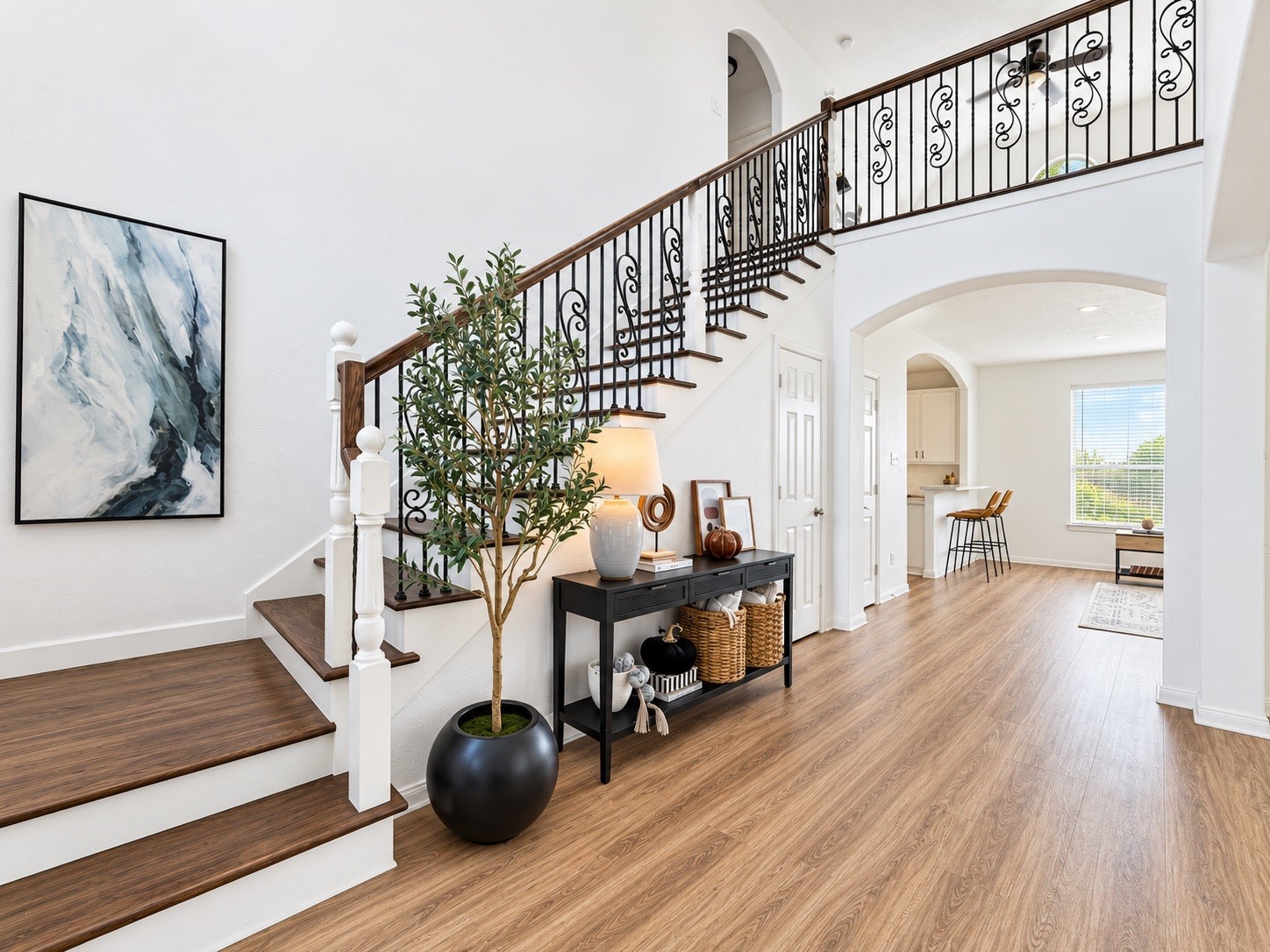 Grand entryway featuring elegant hardwood floors and a sweeping staircase with intricate wrought-iron detailing, setting a welcoming tone for the home.