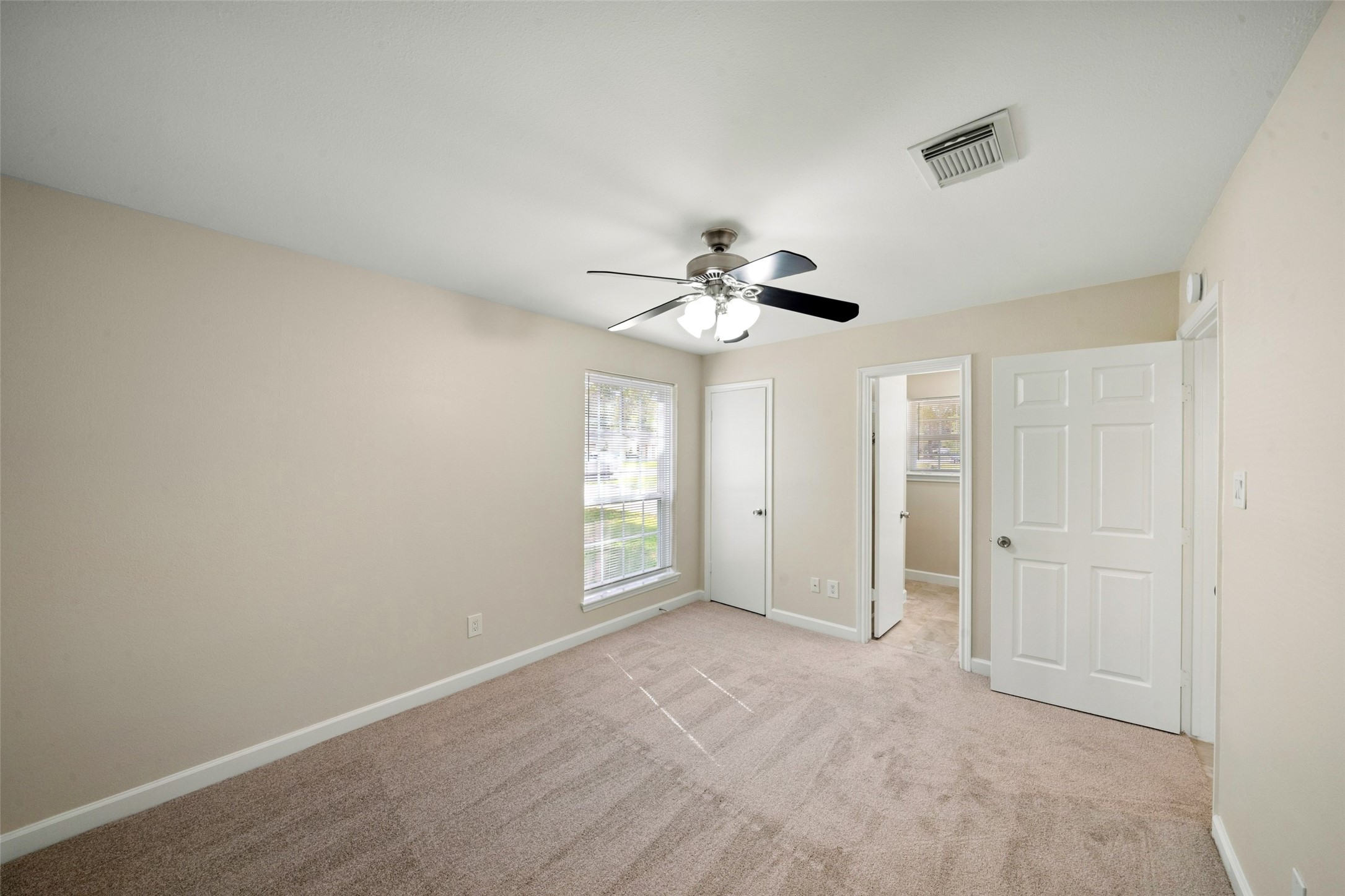 This spacious primary bedroom offers a bright, comfortable feel with brand-new carpet throughout the bedroom and closet. The windows feature new mini blinds and allow an ample amount of natural light to fill the room, creating a warm and inviting atmosphere. Neutral finishes, a ceiling fan, and convenient access to the primary bathroom complete the space.