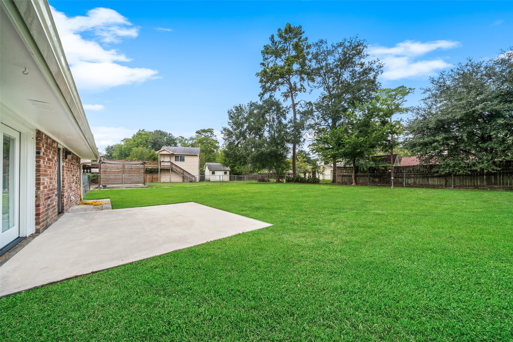 This expansive backyard offers plenty of open green space, mature shade trees, and a large concrete patio perfect for outdoor seating, grilling, or entertaining. The spacious lawn provides ample room for children, pets, gardening, or future outdoor additions, creating a versatile and inviting area for relaxing and enjoying the outdoors.